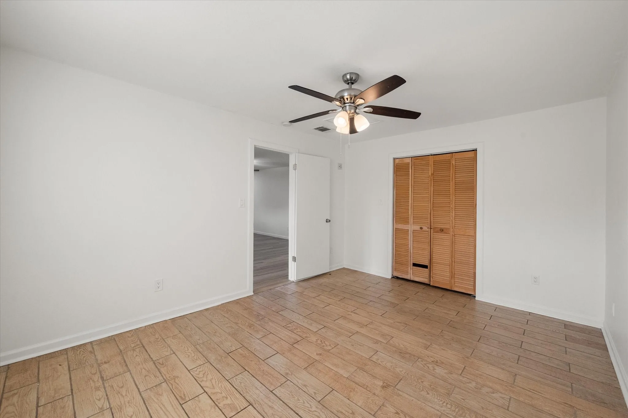 Primary bedroom featuring wood like ceramic tile flooring.