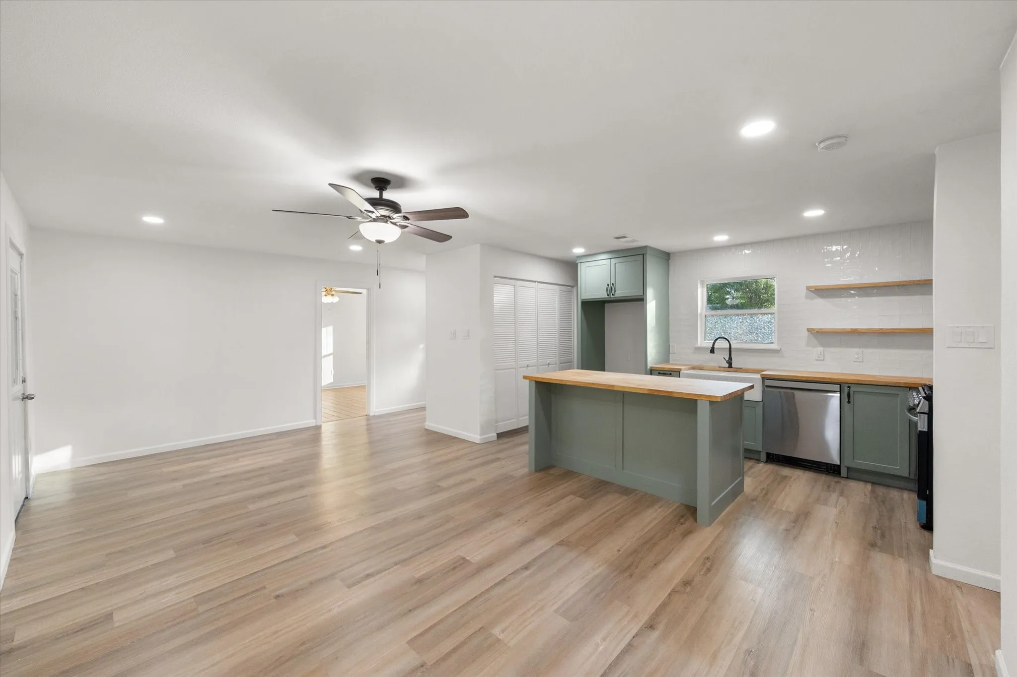 Kitchen and living area featuring wood looking ceramic flooring upgraded kitchen painted cabinets and LED lights.