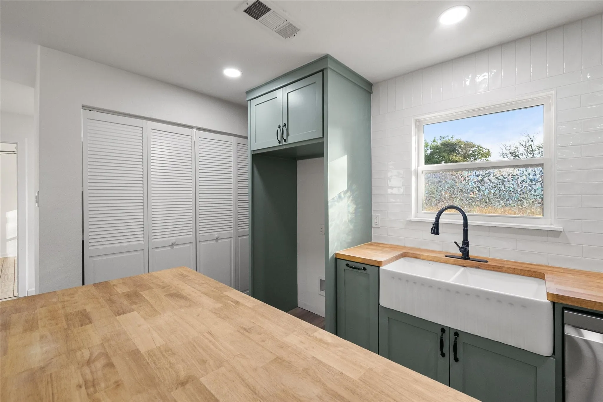 Hardwood butcher block countertops, dual-farmhouse sink with matte black faucet, painted, shaker style cabinetry, white subway tile backsplash, SS appliances and LED Lights.