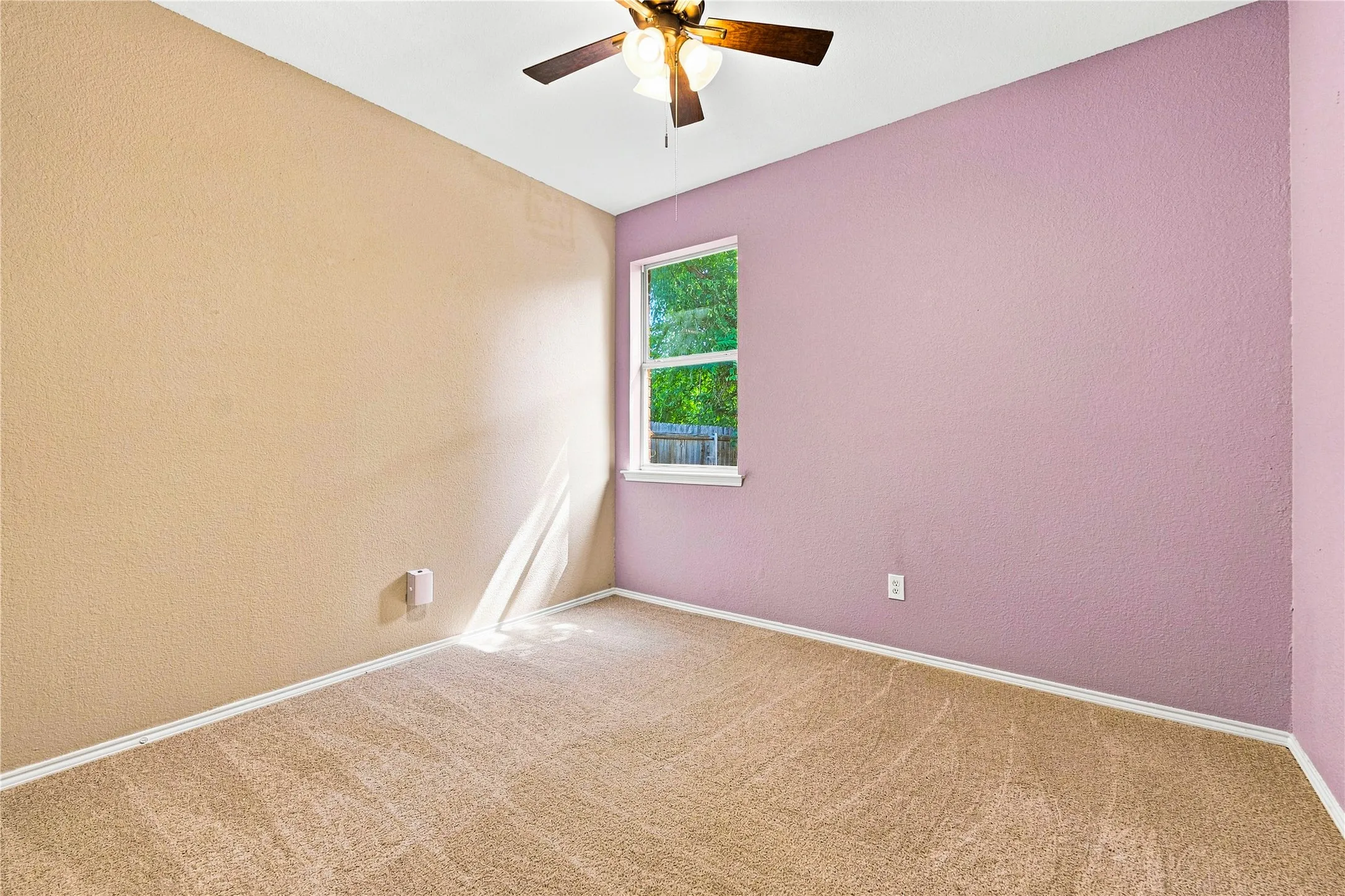 Neutral tone wall with a contrasting accent wall, carpeted flooring, and a ceiling fan with integrated lighting