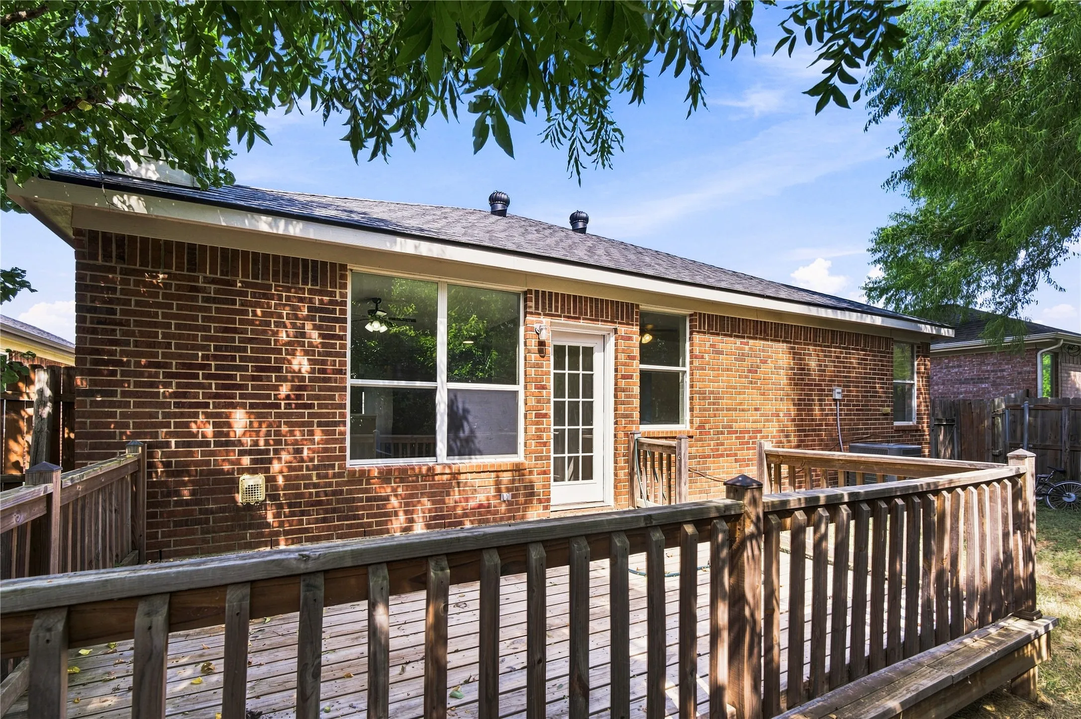 Expansive outdoor deck with built-in bench seating, brick exterior, and multiple large windows