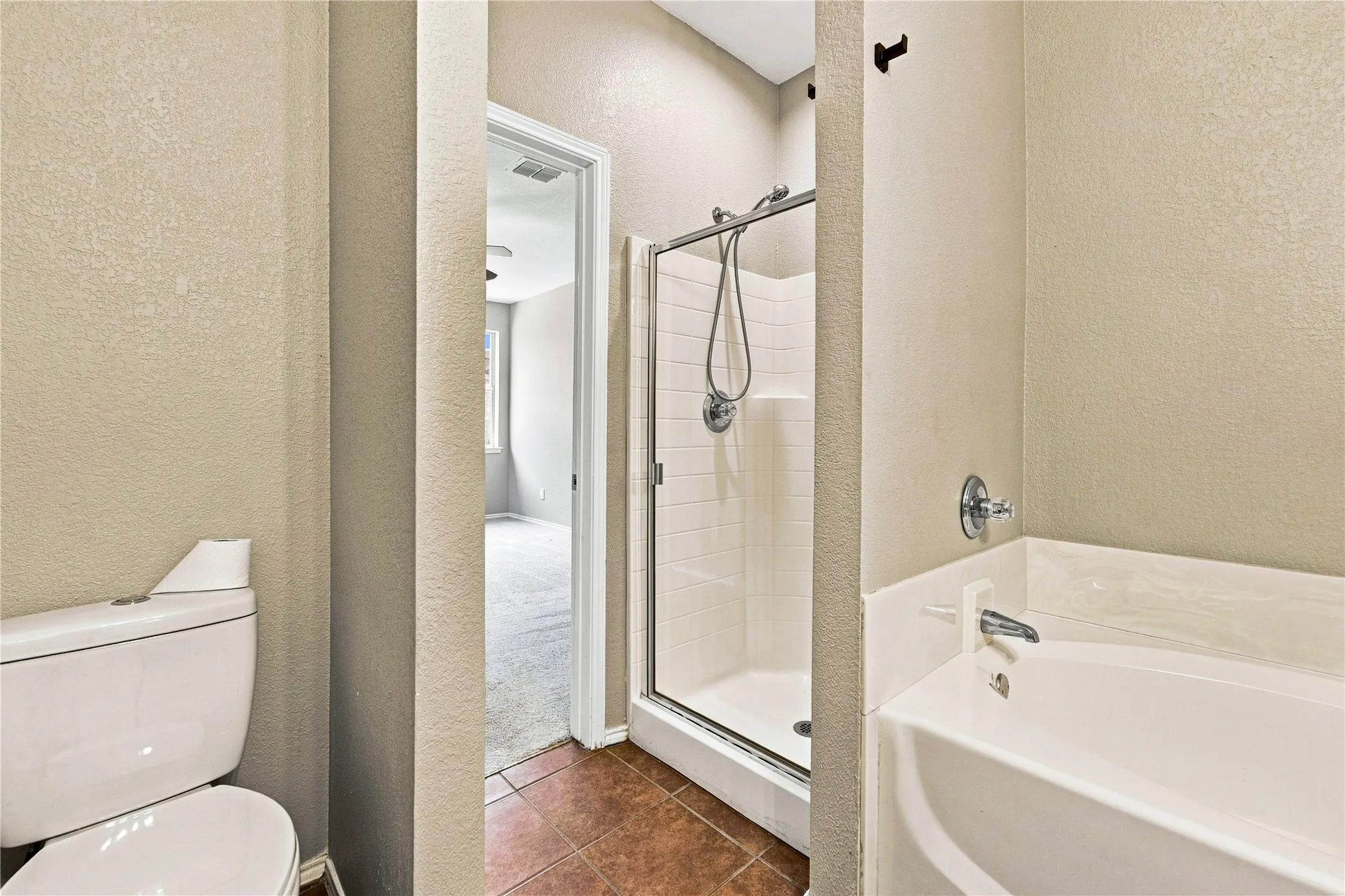Walk-in shower with clear glass enclosure, separate bathtub with chrome fixtures, and tiled flooring