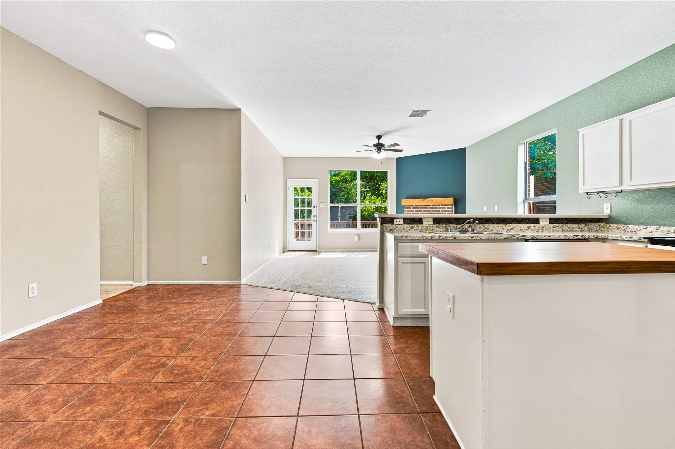 Open-concept living space with tile flooring, a built-in kitchen island, and white cabinetry