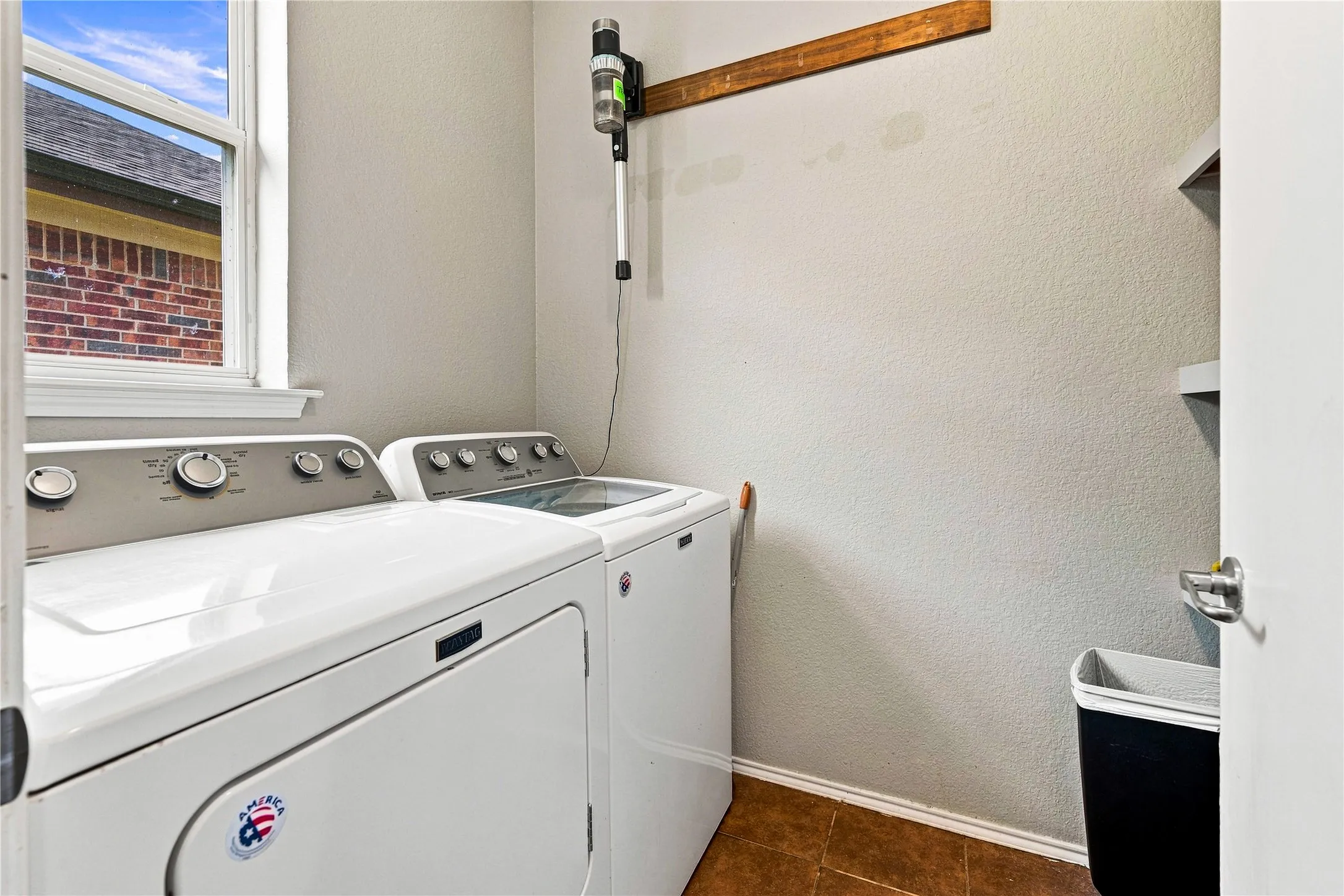 Laundry area with a window, tile flooring, and integrated shelving