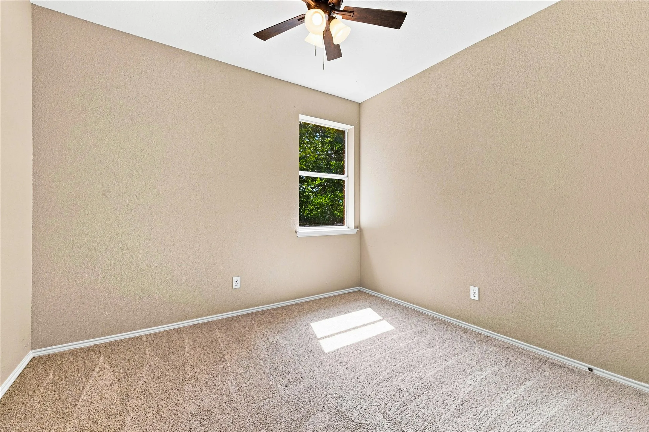 Neutral tone walls, carpet flooring, a multi-pane window, and a ceiling fan with integrated lighting