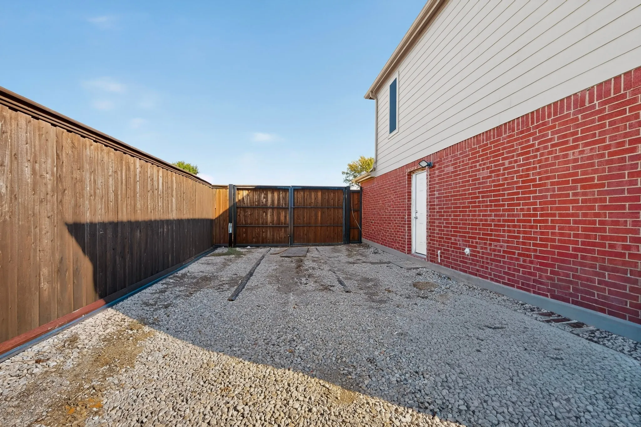Gravel side yard with 8' board-on-board wood privacy fencing and double wood gates. Ideal for parking large truks, boats, trailers, etc.