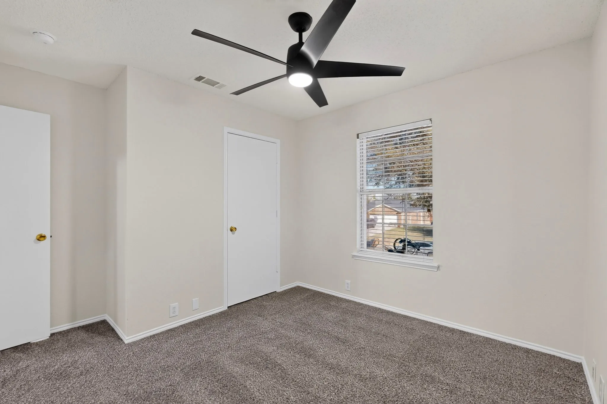 Recently painted, plush carpet flooring, upgraded ceiling fan, window with blinds, and white trim throughout.