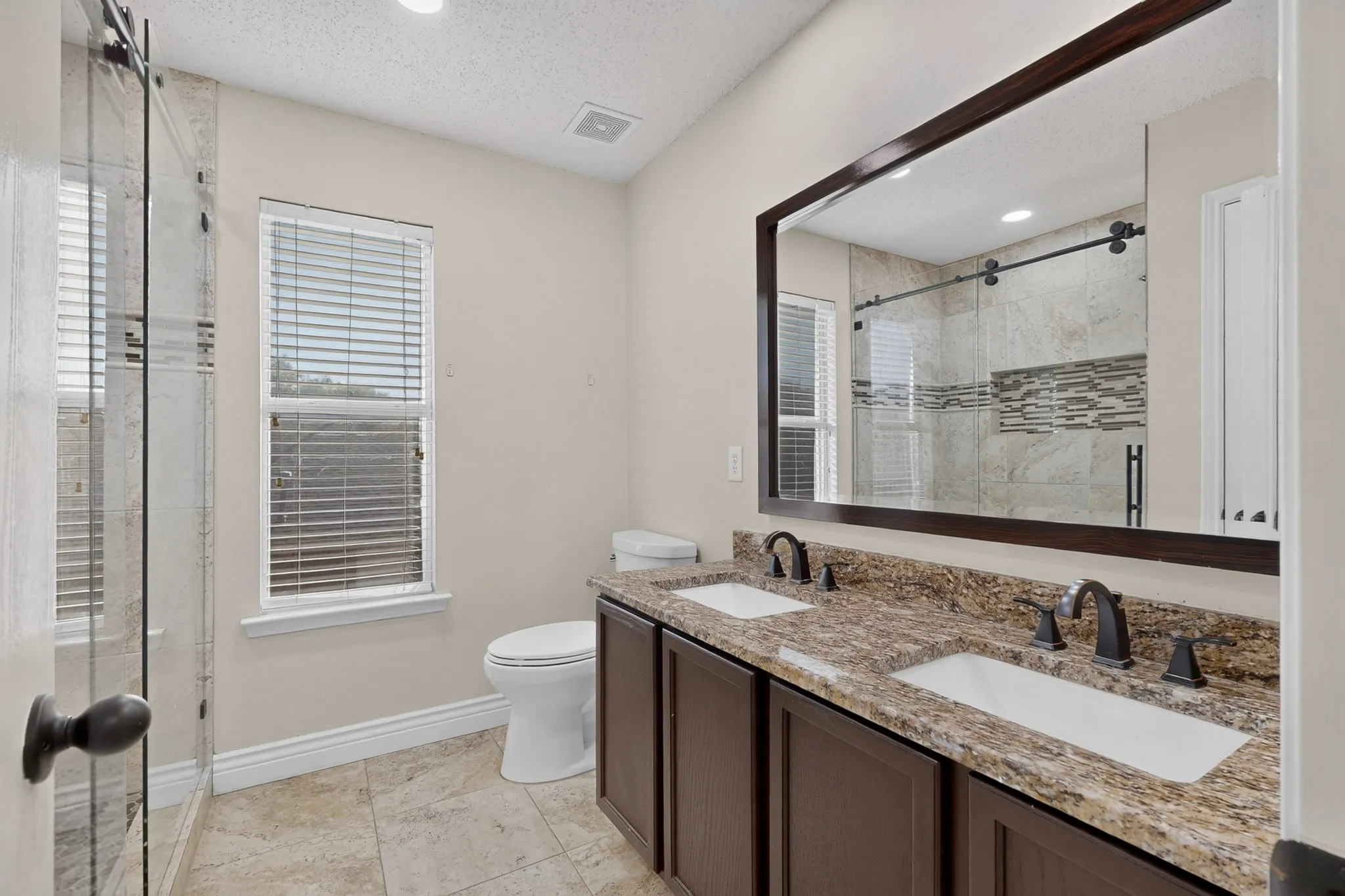 Recently remodeled full bathroom with double vanity with granite countertop and dual undermount sinks.
