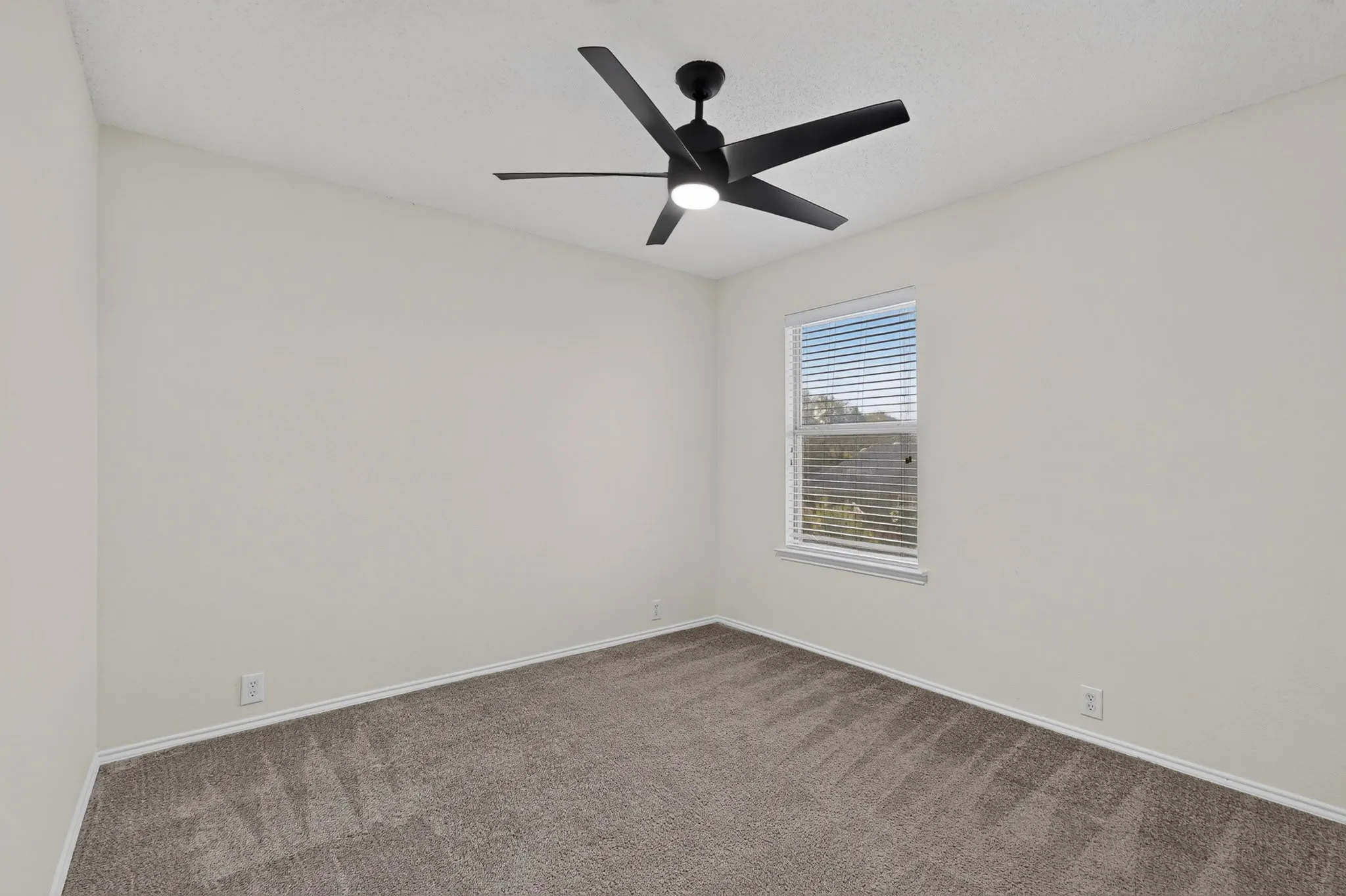 Recently painted, plush carpet flooring, upgraded ceiling fan, window with blinds, and white trim throughout.
