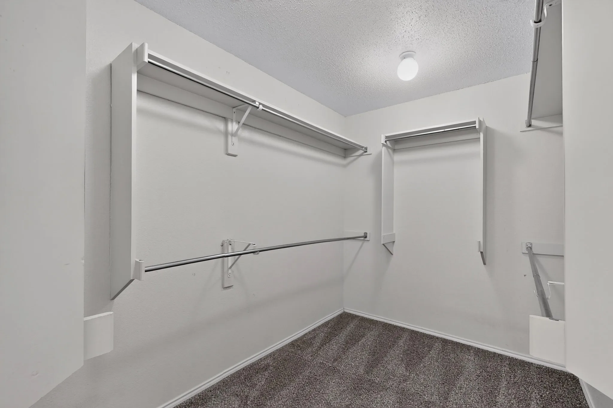 Spacious closet featuring multiple storage rods and shelving
