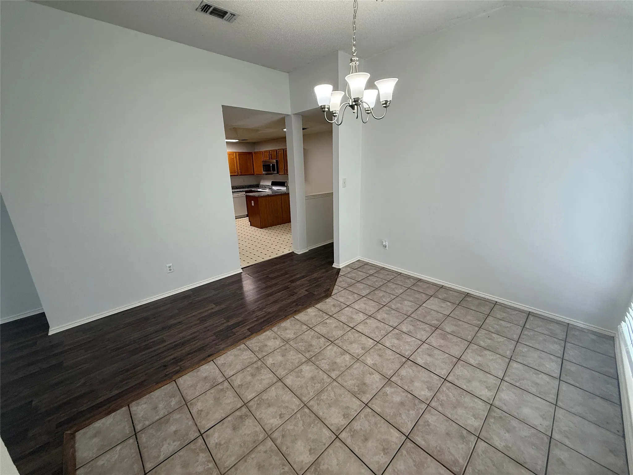 Ceramic tile flooring, wood-finish flooring, and a five-light chandelier