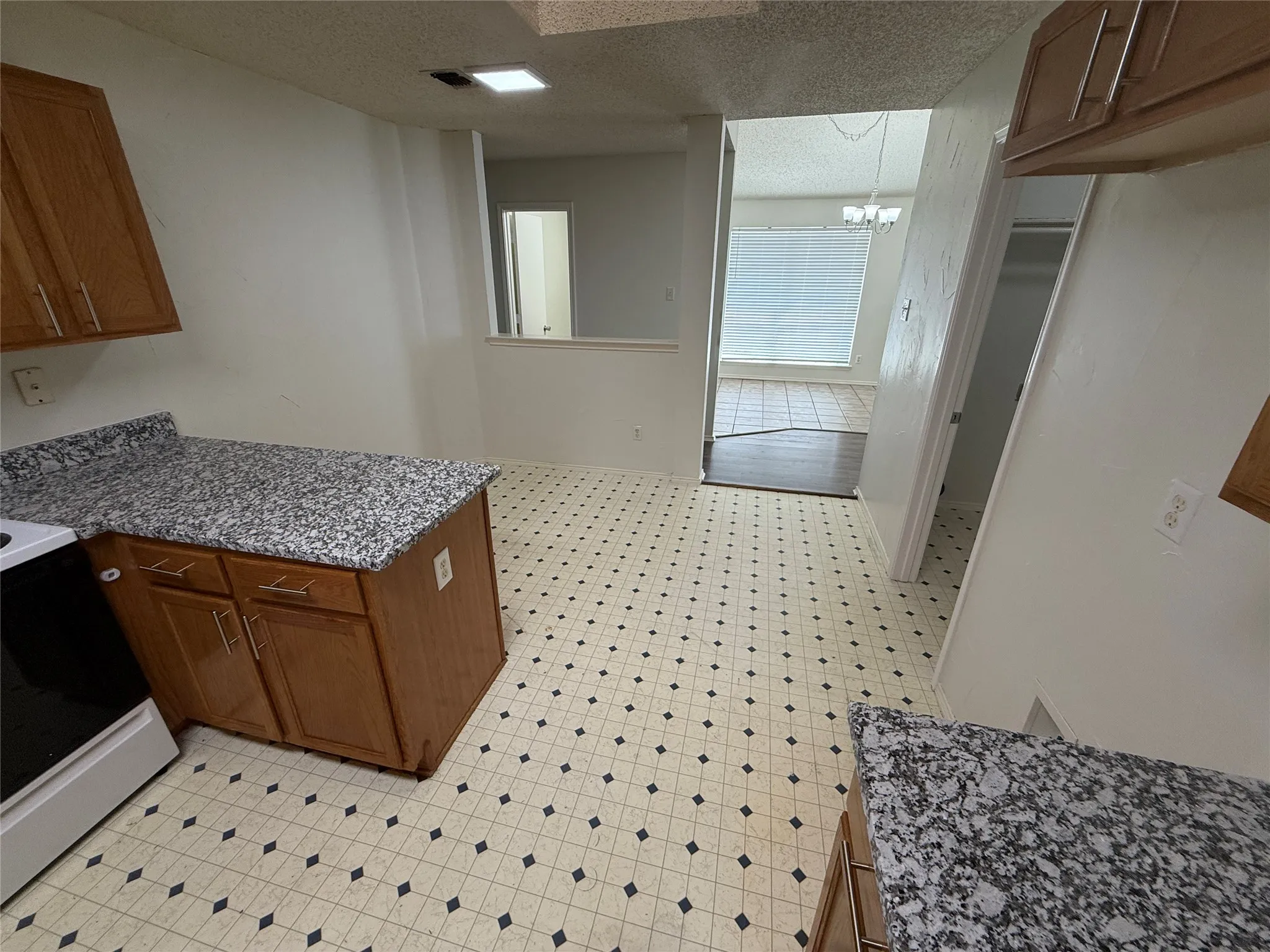 Kitchen featuring patterned floor tiles, wood-finish cabinetry, and speckled countertops