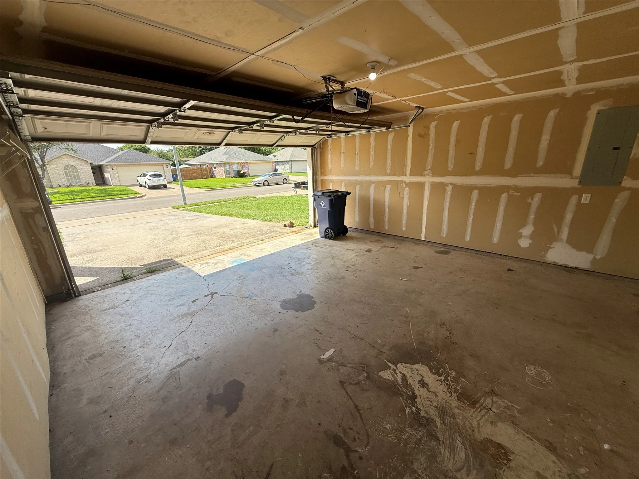Garage space featuring an overhead door, concrete flooring, and ceiling-mounted lighting