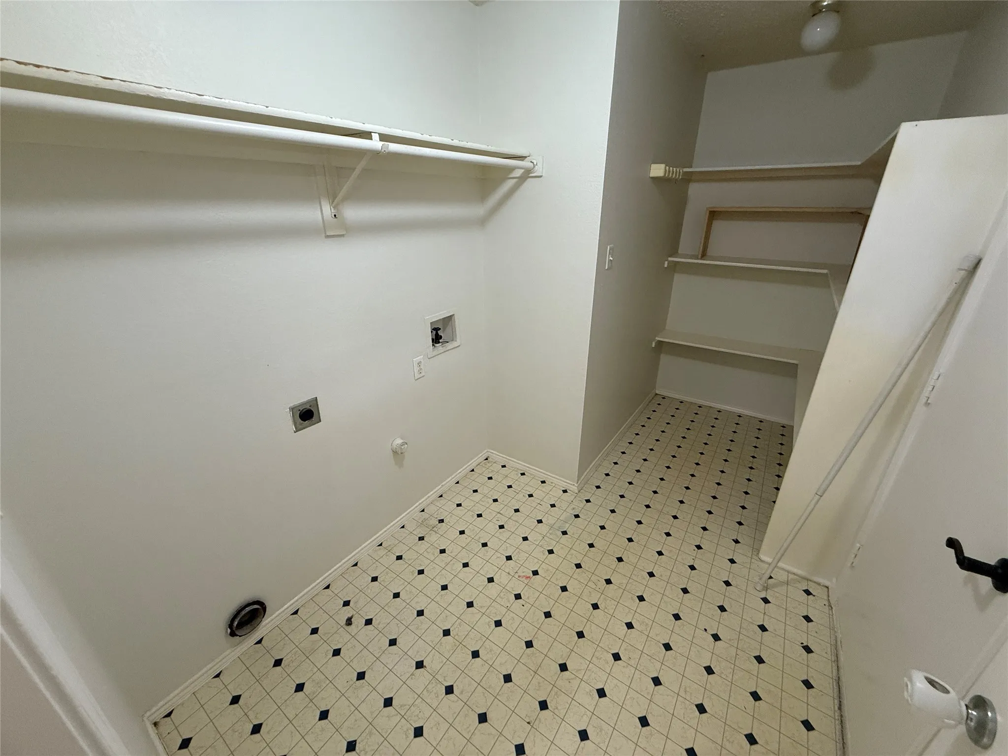 Utility room with patterned flooring, built-in shelving, a clothes rod, and appliance hookups
