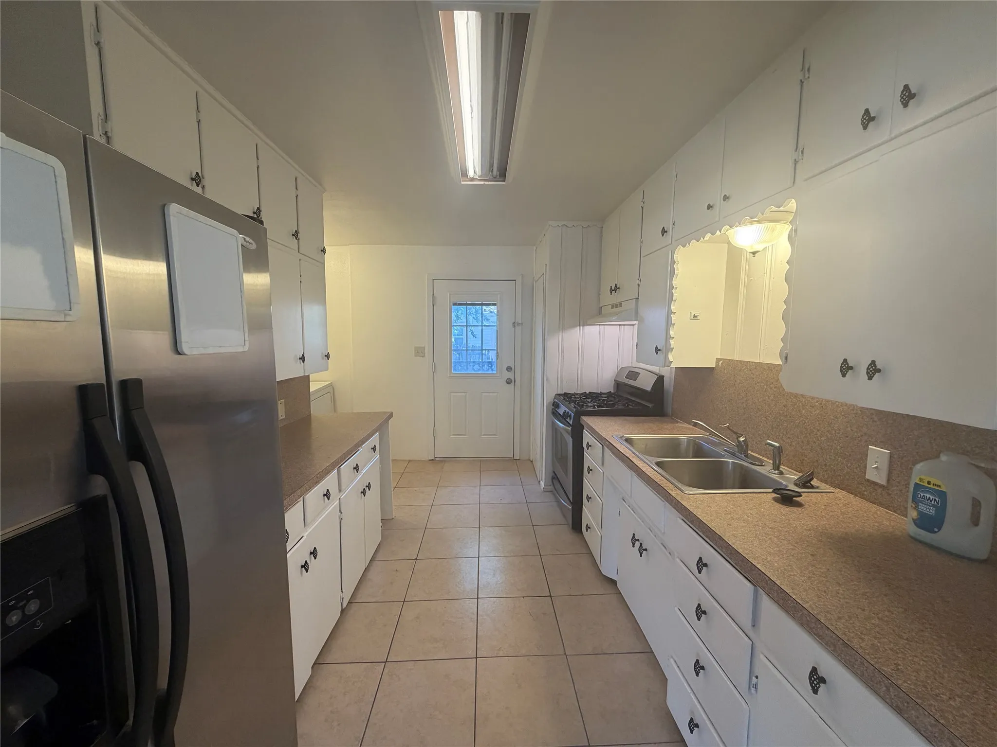 Kitchen with white cabinetry, dual basin stainless steel sink, and tile flooring