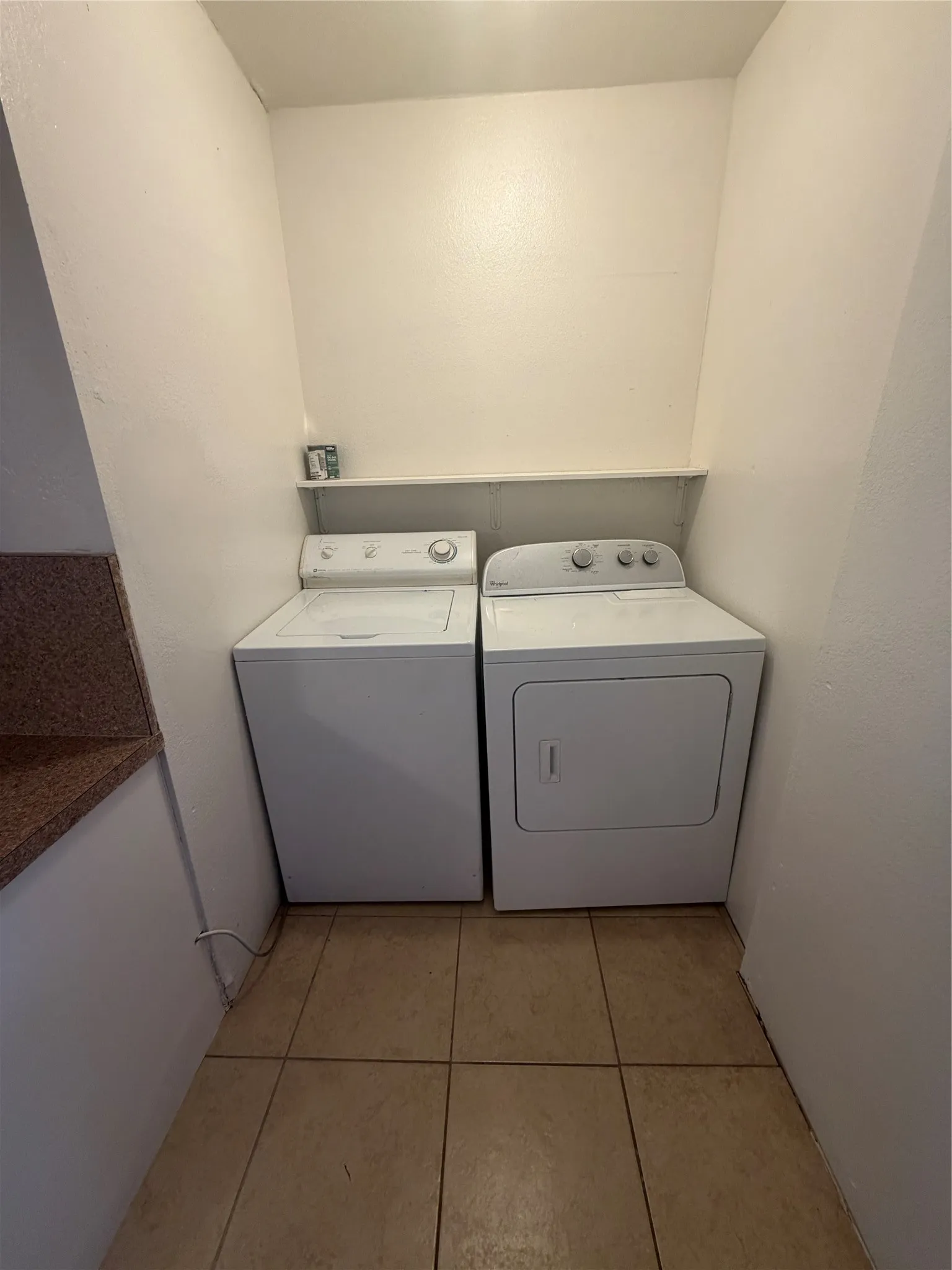 Laundry area with a full-size washer and dryer, tile flooring, and an integrated shelf