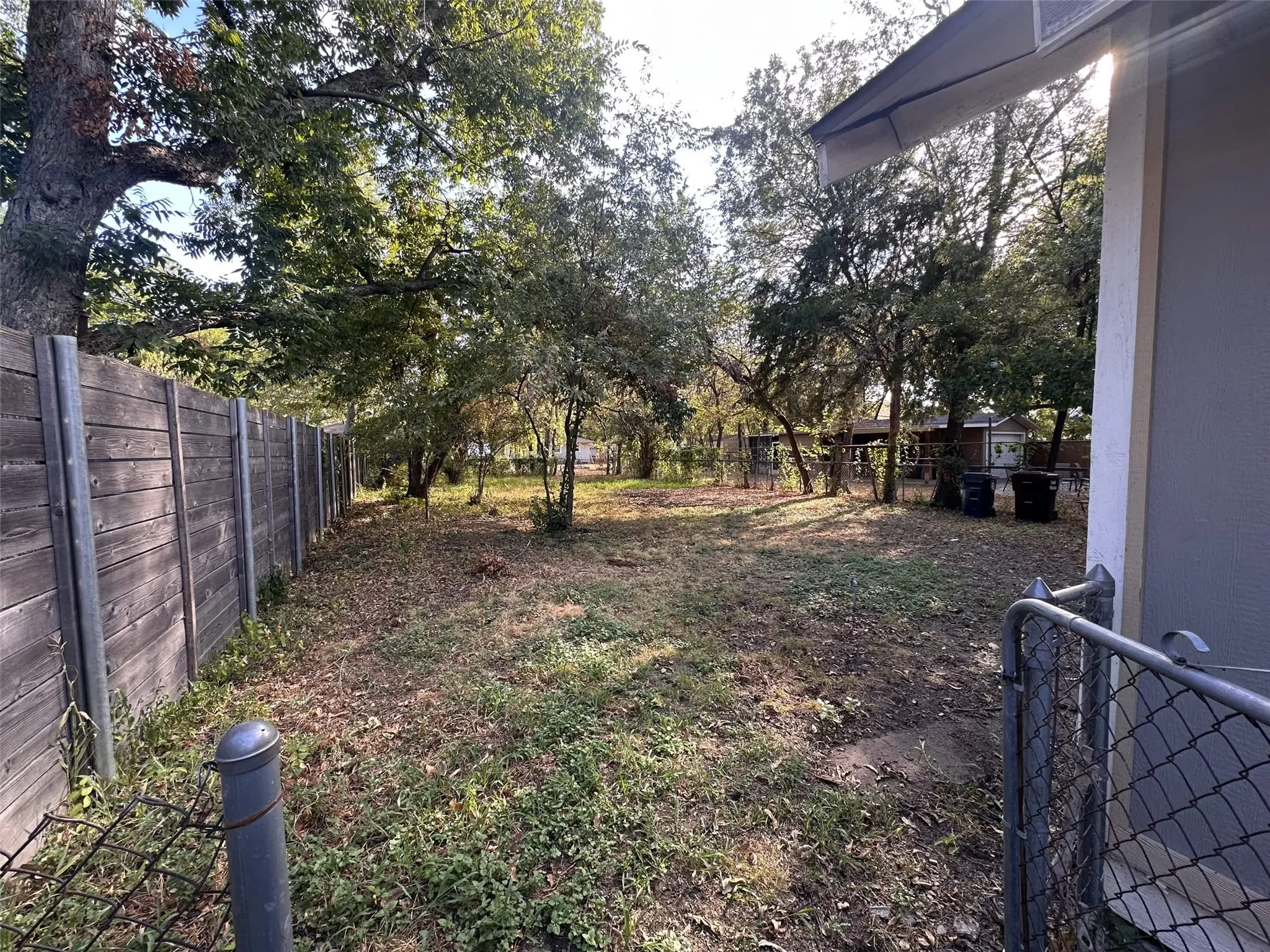 Expansive yard featuring mature trees and a wood-panel fence