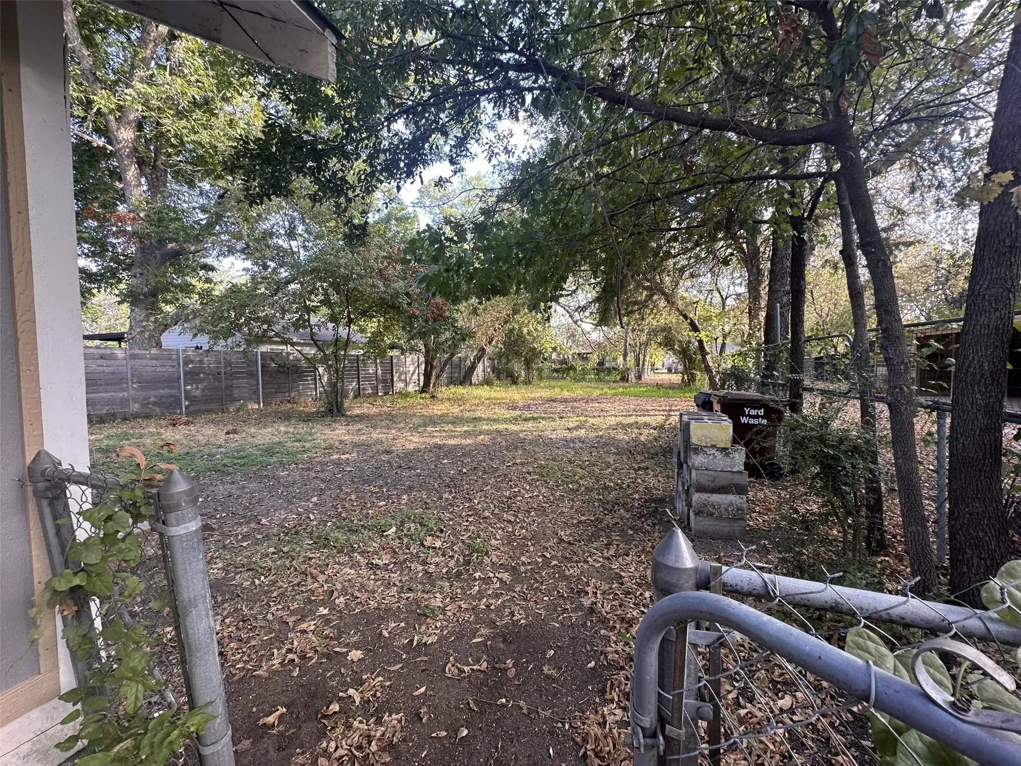 Expansive backyard featuring mature trees and a chain-link fence