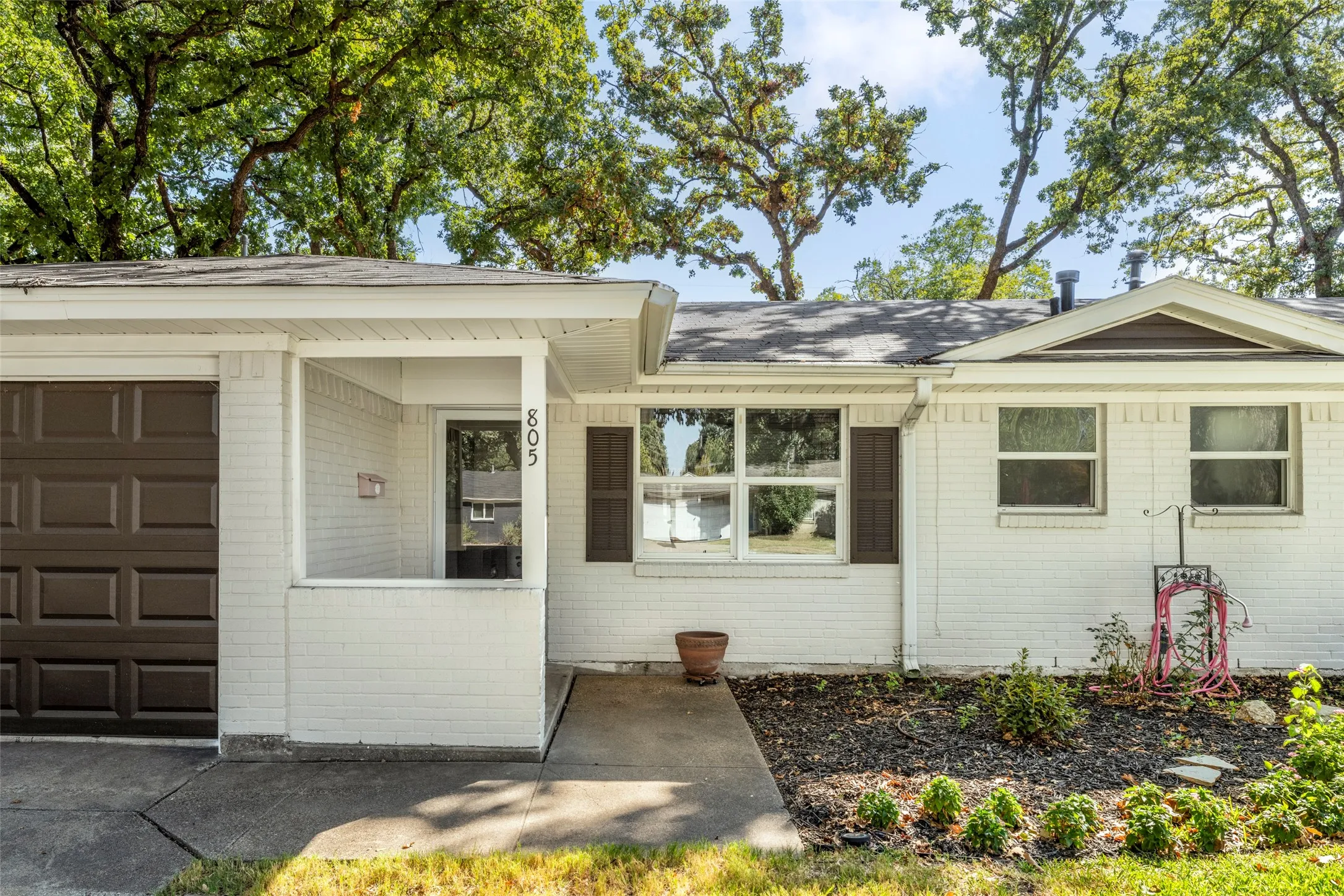 White brick exterior with a dark brown garage door