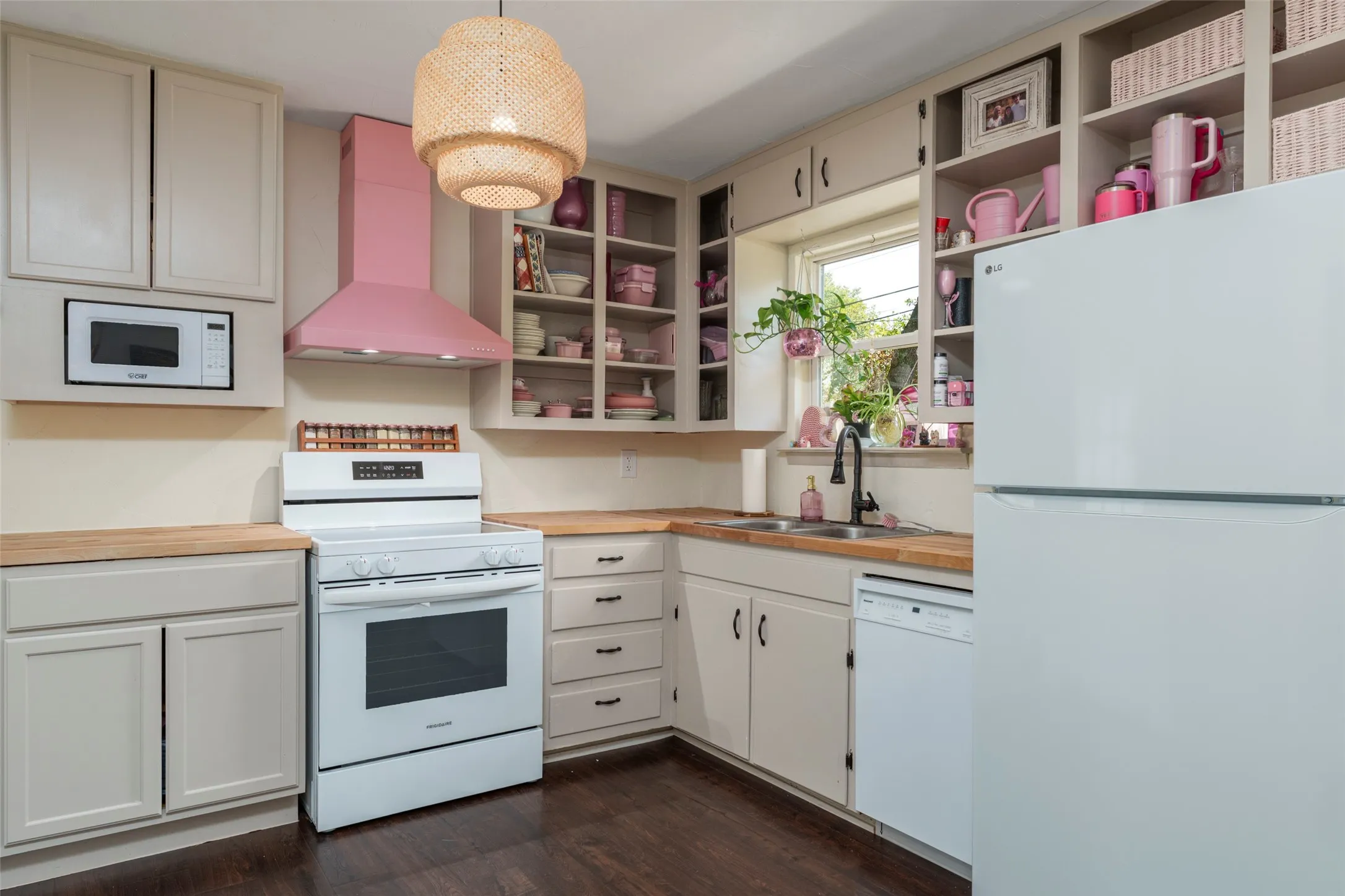 Kitchen featuring wood-finish countertops, built-in shelving, white appliances, and a pink range hood