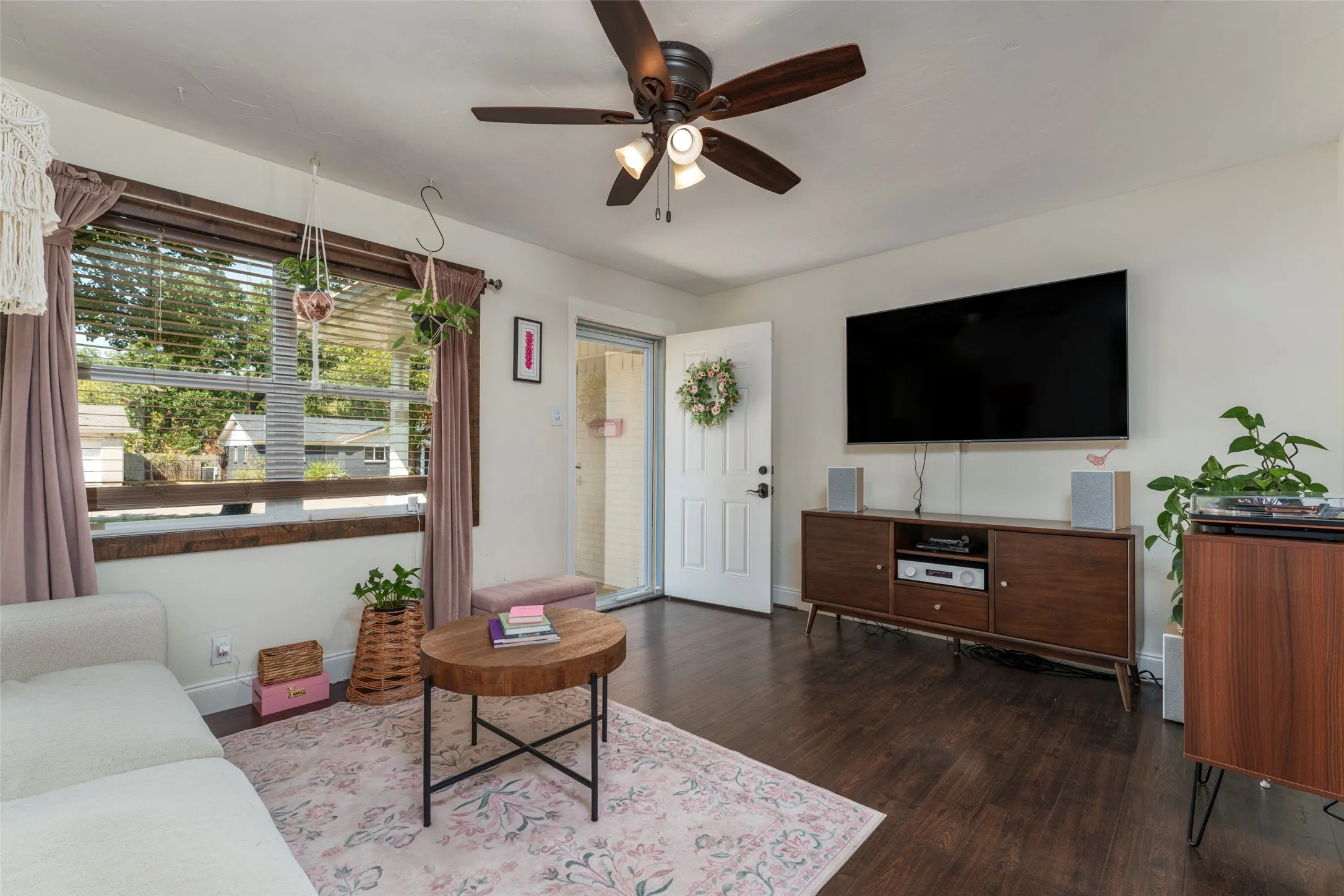 Wood-finish flooring, white walls, and a ceiling fan with integrated lighting