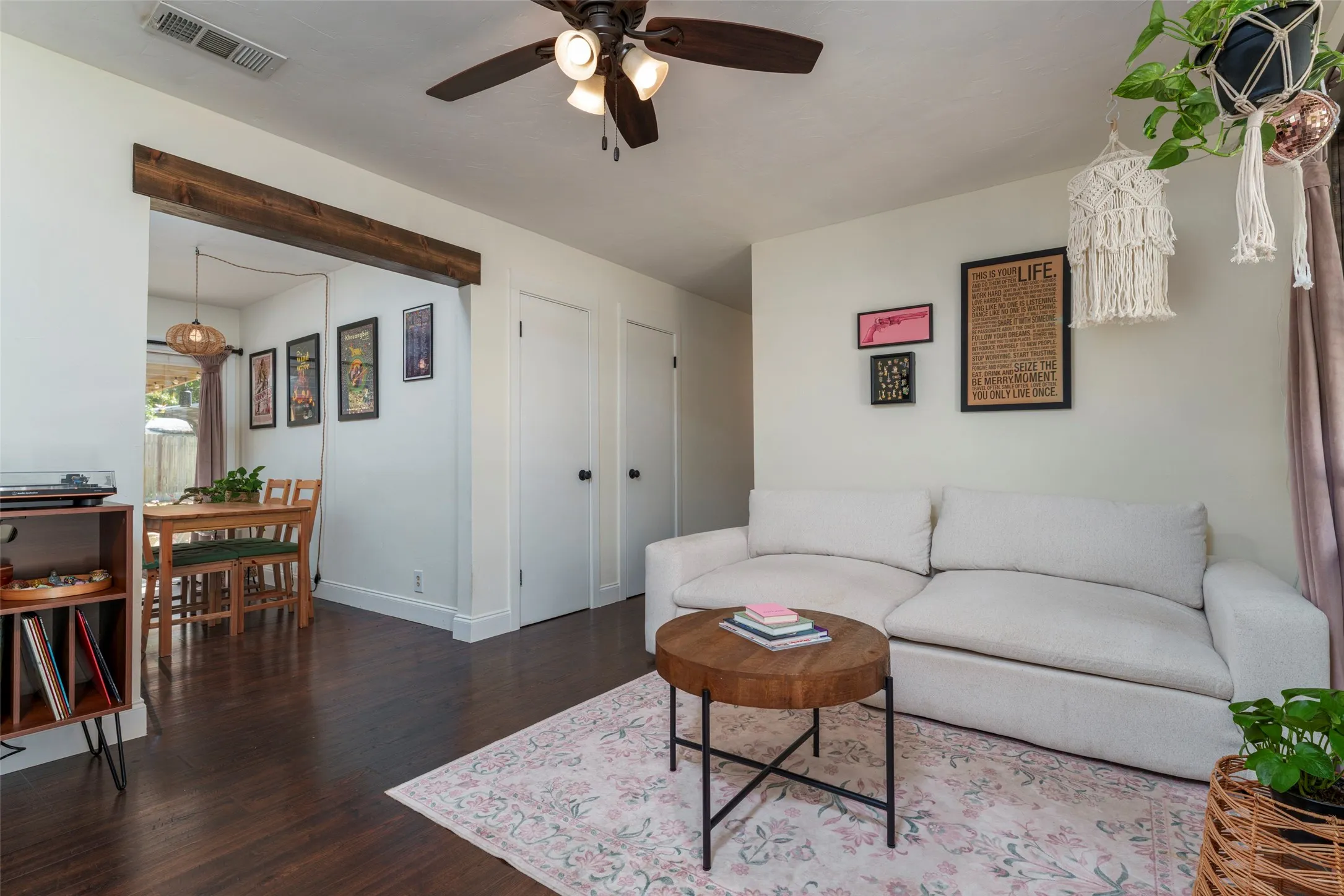 Wood-finish flooring throughout, featuring a decorative exposed beam and a ceiling fan with integrated lighting