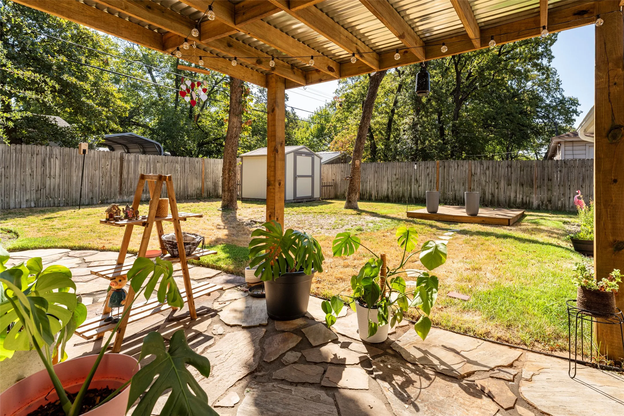 Covered patio with a corrugated roof, exposed wood beams, and a flagstone surface