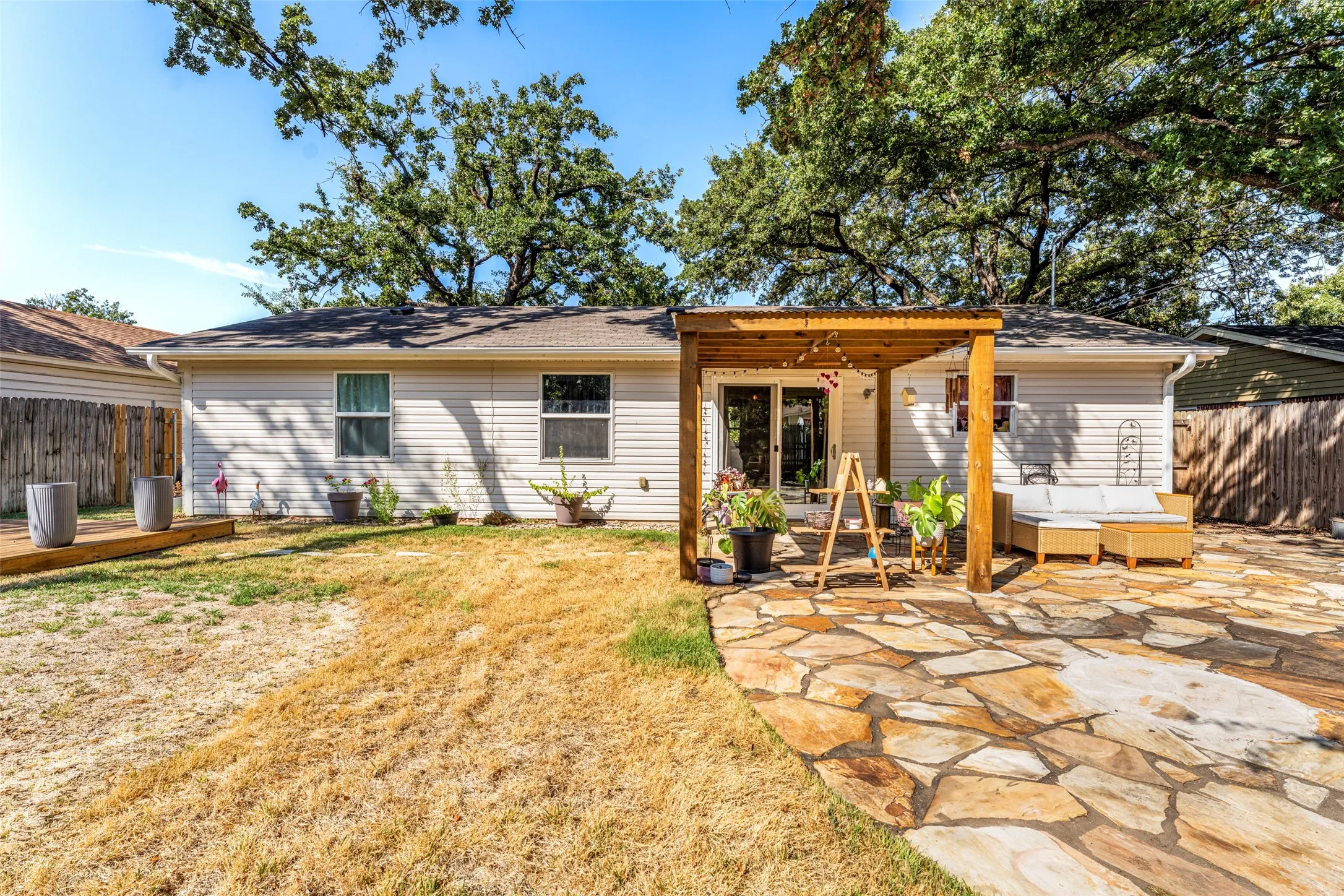 Expansive flagstone patio area with an attached wood pergola, complemented by a secondary wood deck