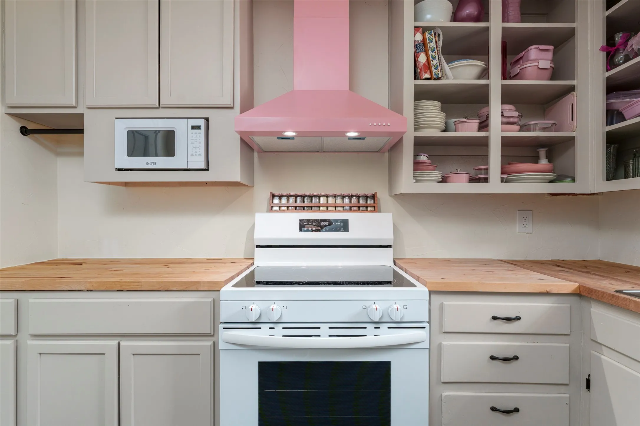 Kitchen featuring light-toned cabinetry, wood-finish countertops, and a built-in microwave