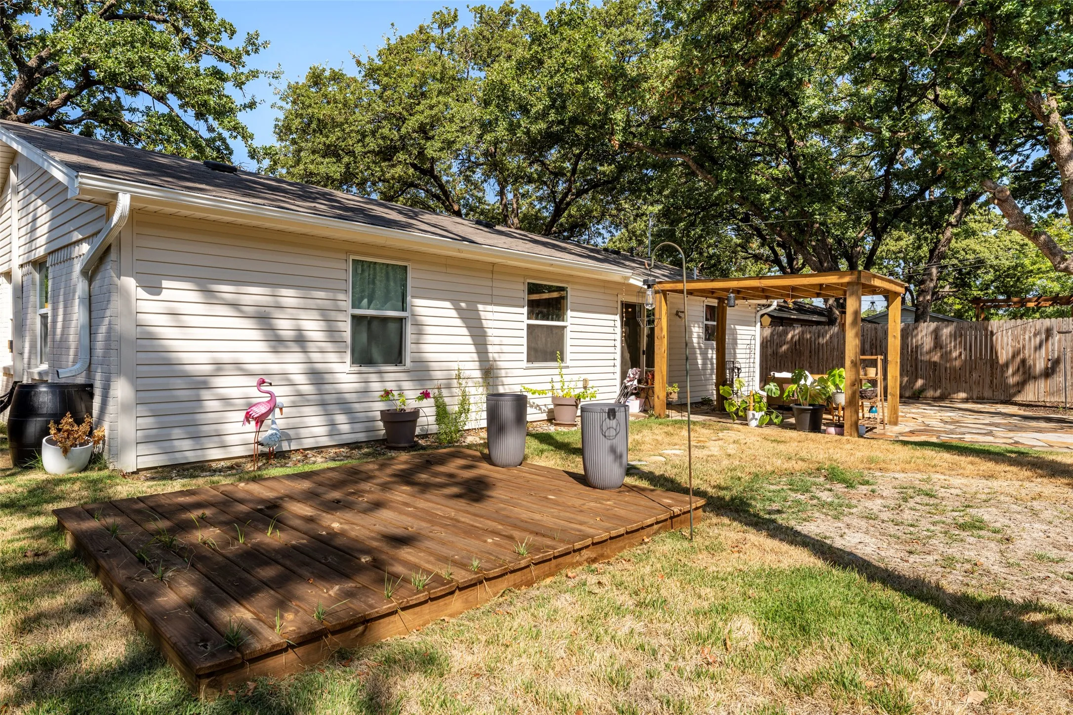 Exterior featuring horizontal siding, multiple windows, a wooden deck, a wooden pergola, and a wooden fence
