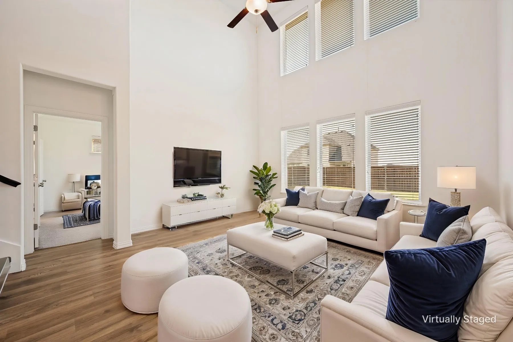 Soaring ceilings with an exposed beam, wood-finish flooring, and multiple windows