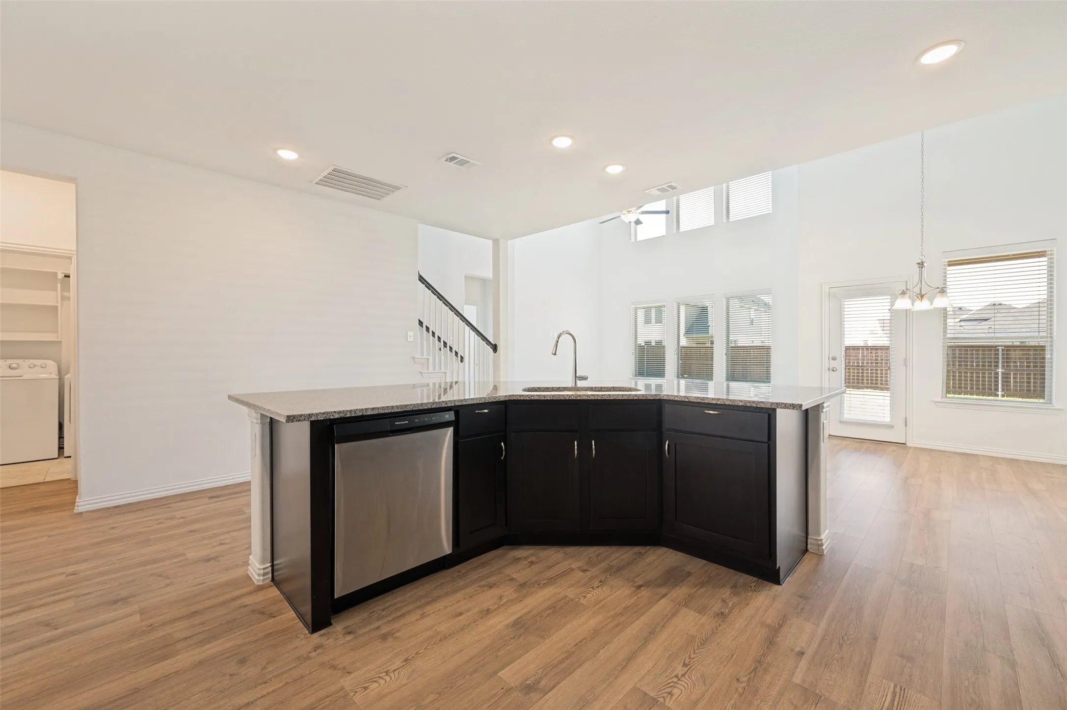 Kitchen island with dark cabinetry, stainless steel dishwasher, and a gooseneck faucet