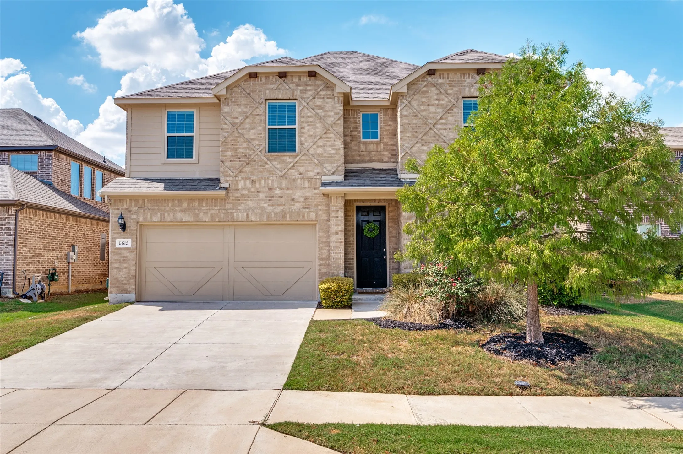 Two-story exterior with a brick and siding facade, a two-car garage, and a concrete driveway