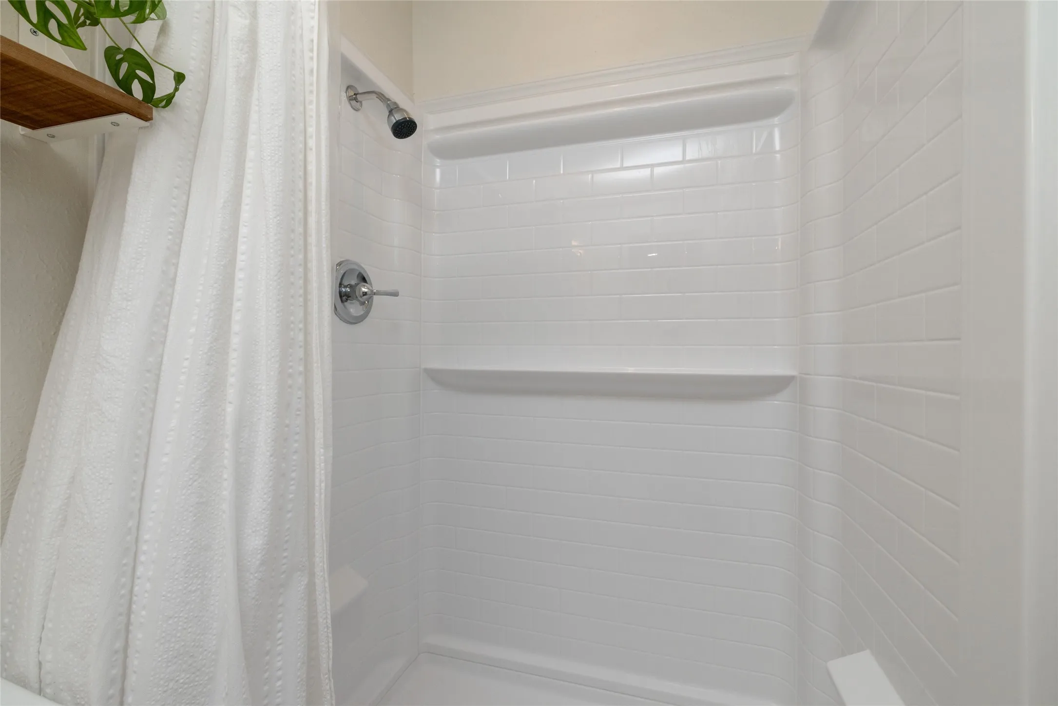 White shower enclosure with integrated shelving and chrome fixtures