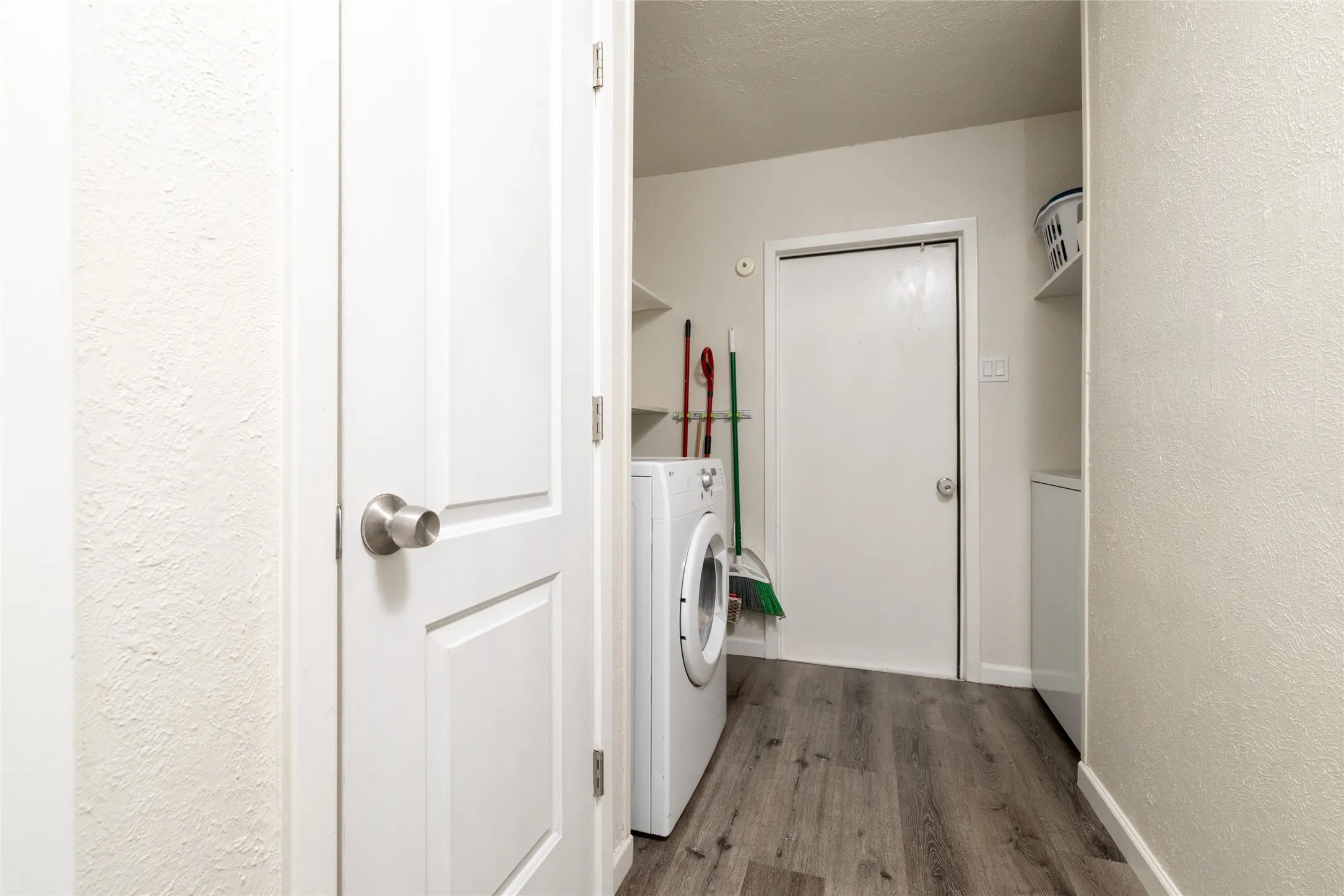 Laundry area featuring wood-finish flooring, white walls, and built-in shelving