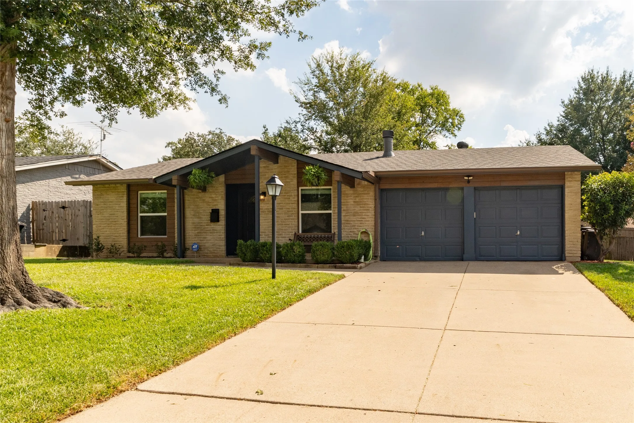Brick facade with a prominent two-car garage, concrete driveway, and a front lawn