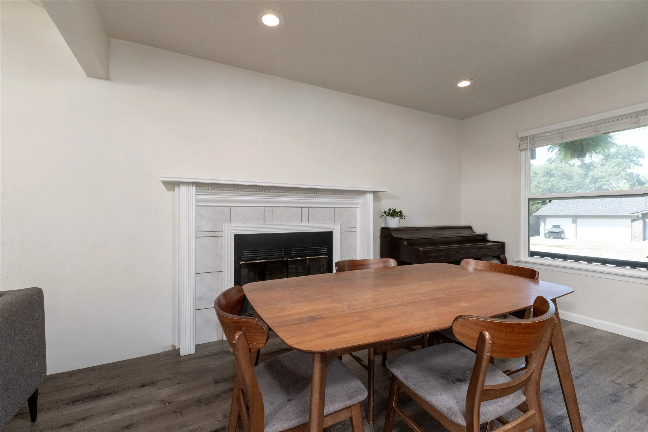 Fireplace with a white mantel and tile surround, recessed lighting, wood-finish flooring, and a large window