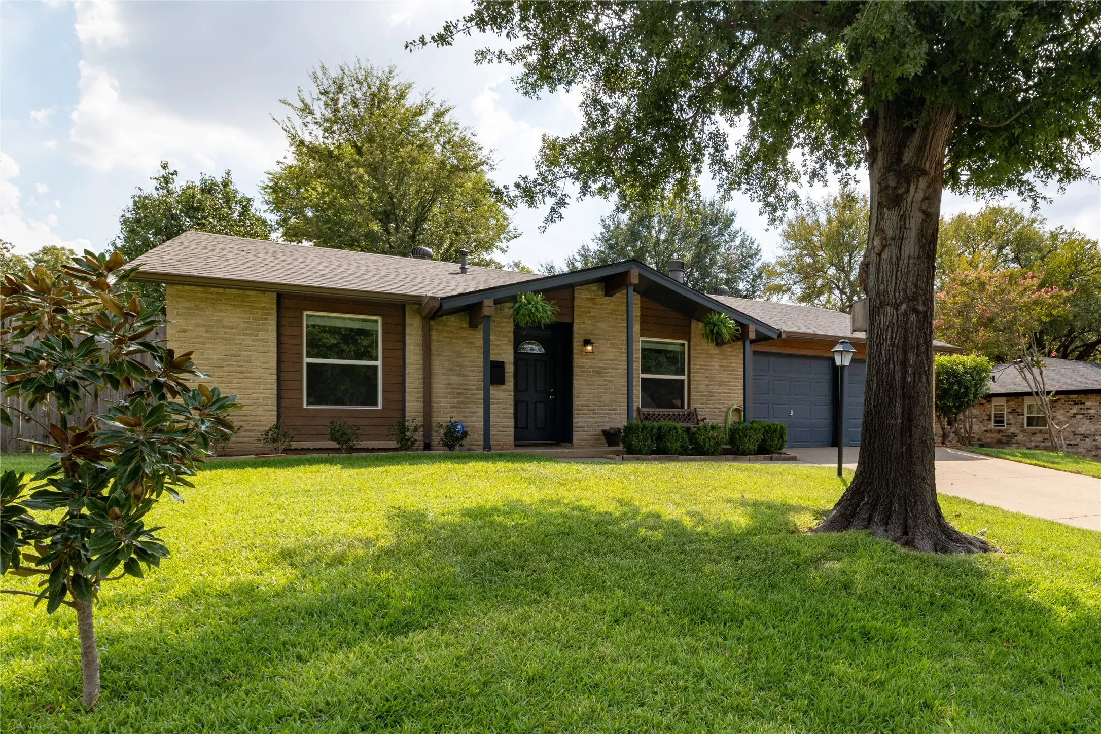 Brick exterior with wood accents, a covered entry, and a dark asphalt shingle roof