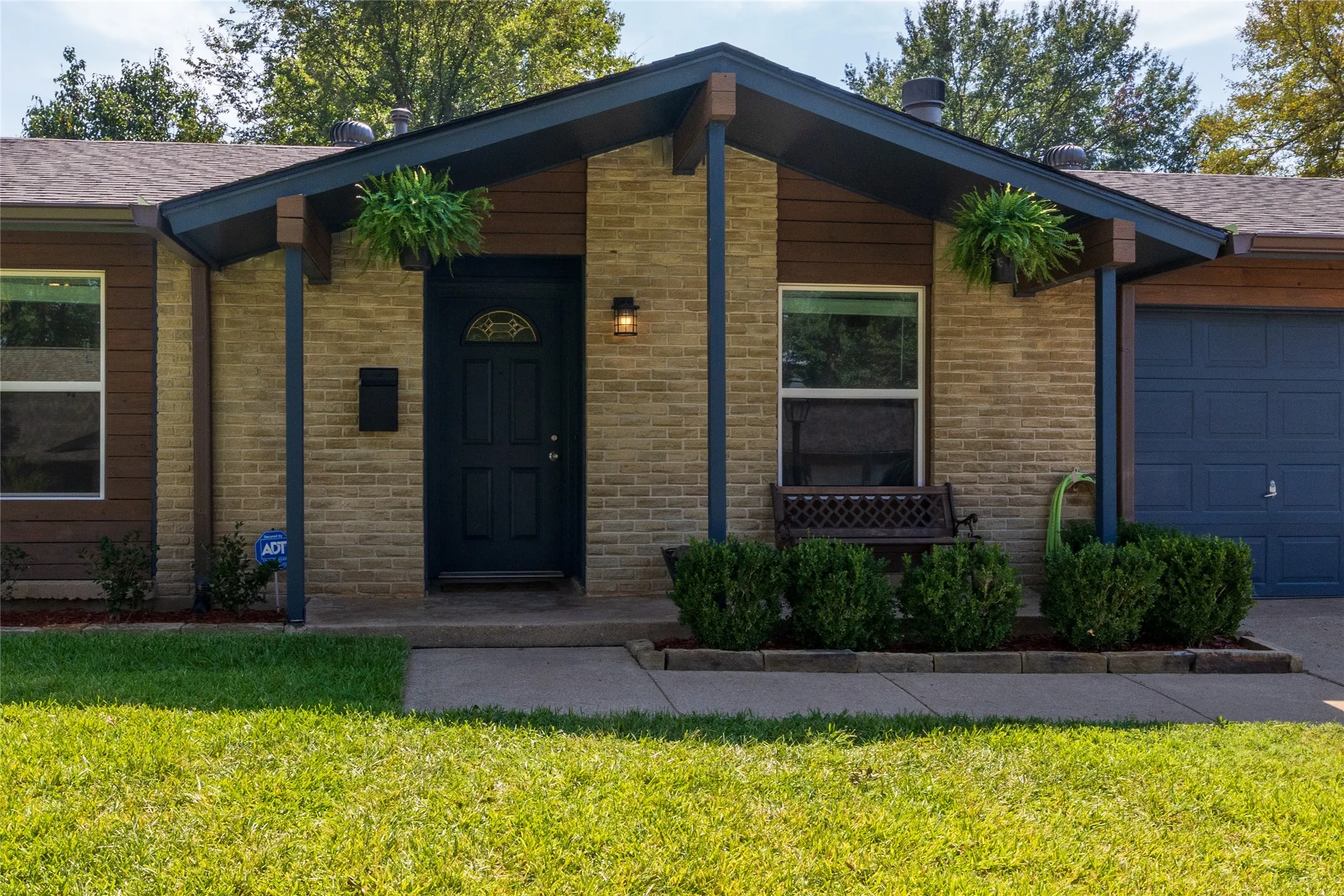 Brick and horizontal wood-panel siding exterior with a dark blue front door and garage door