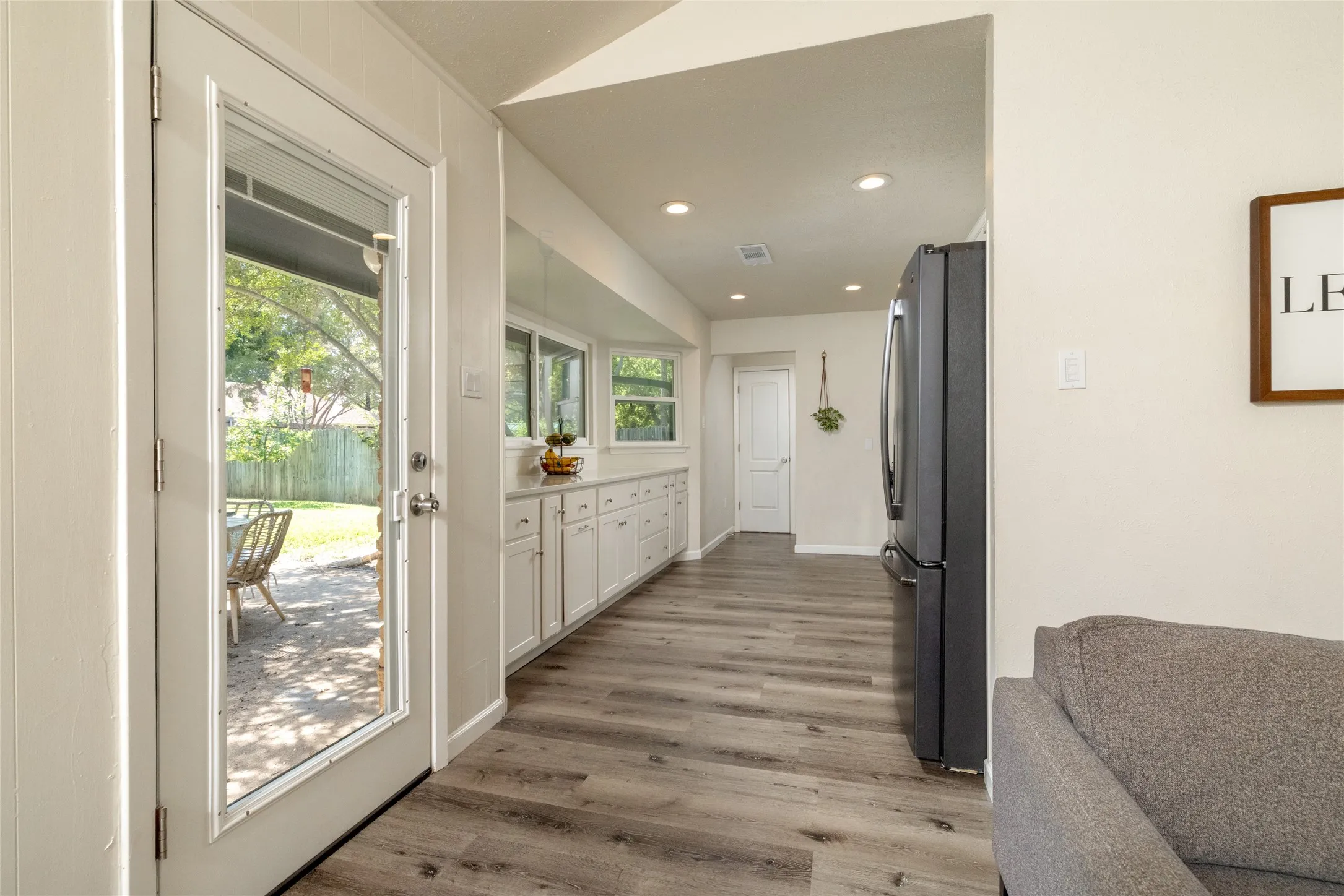 Wood-finish flooring throughout, full-light door, recessed lighting, and built-in white cabinetry with a light-colored countertop