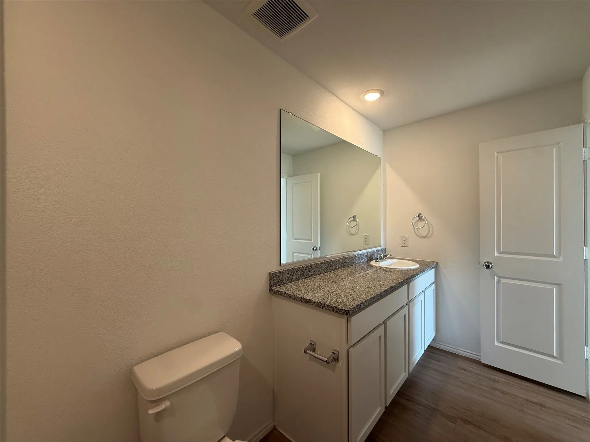 Vanity with a granite-style countertop, white cabinetry, and an integrated sink