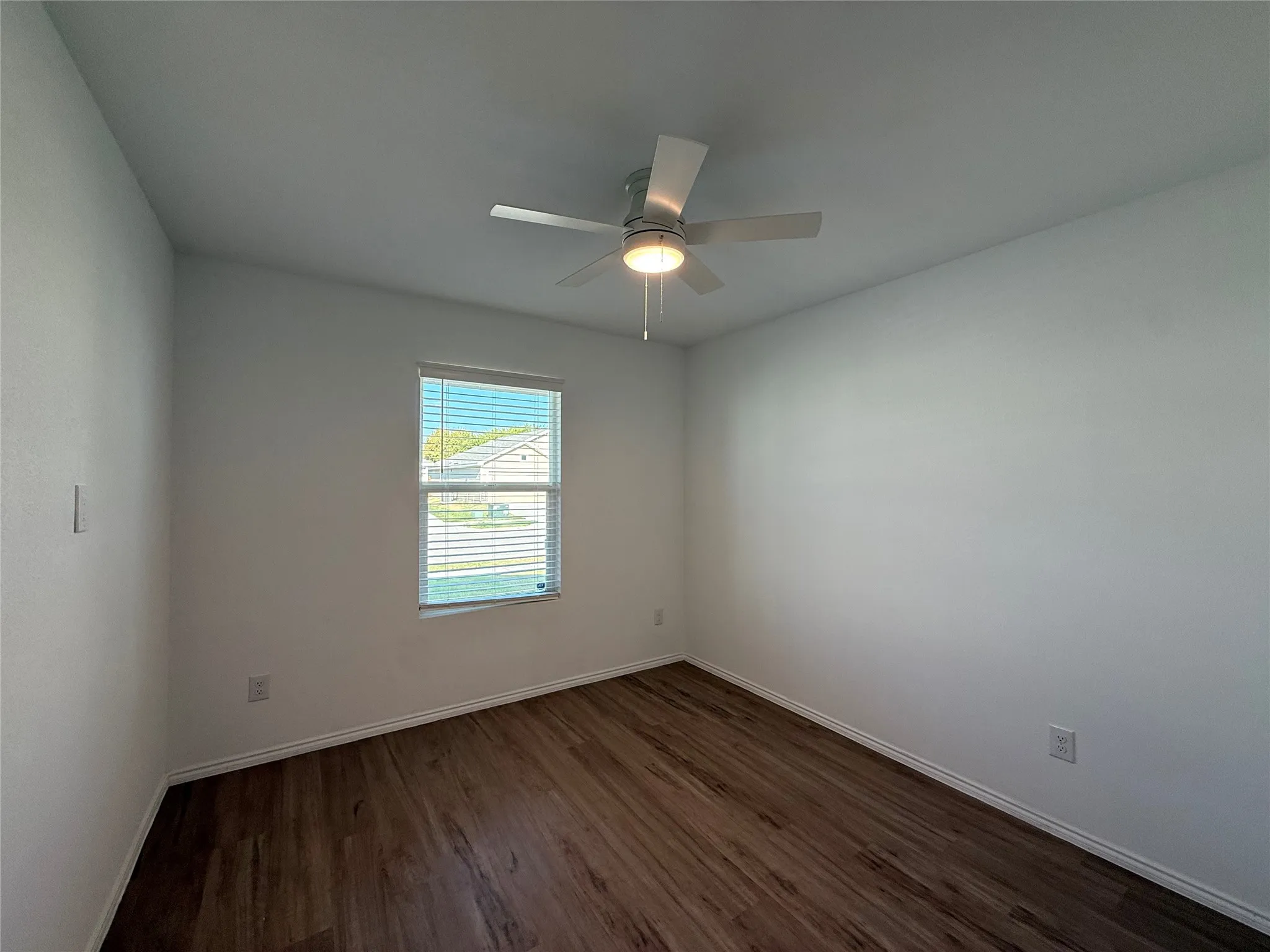 Wood-finish flooring, white walls, and a window with blinds