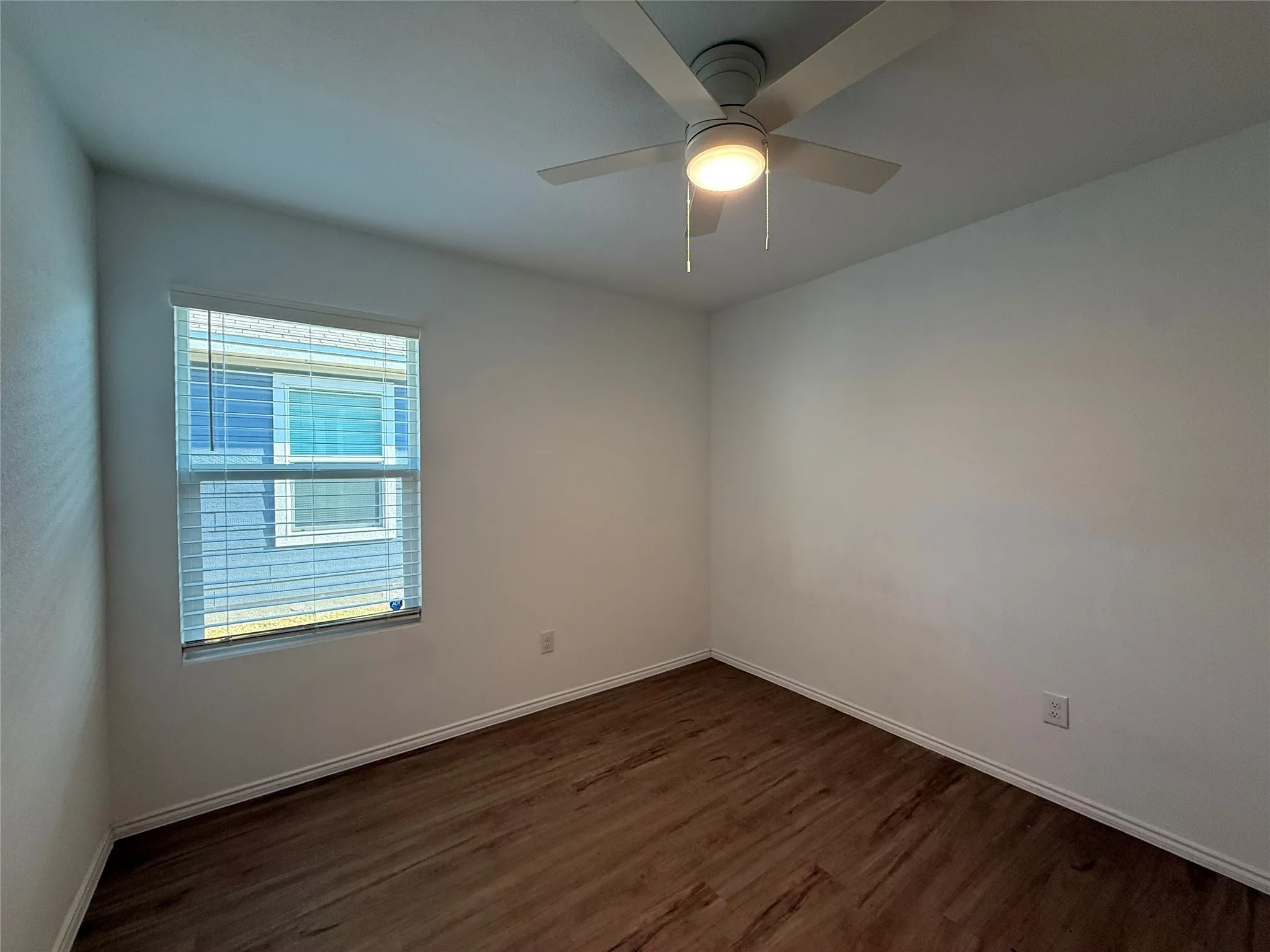Wood-finish flooring, white walls, and a window with horizontal blinds