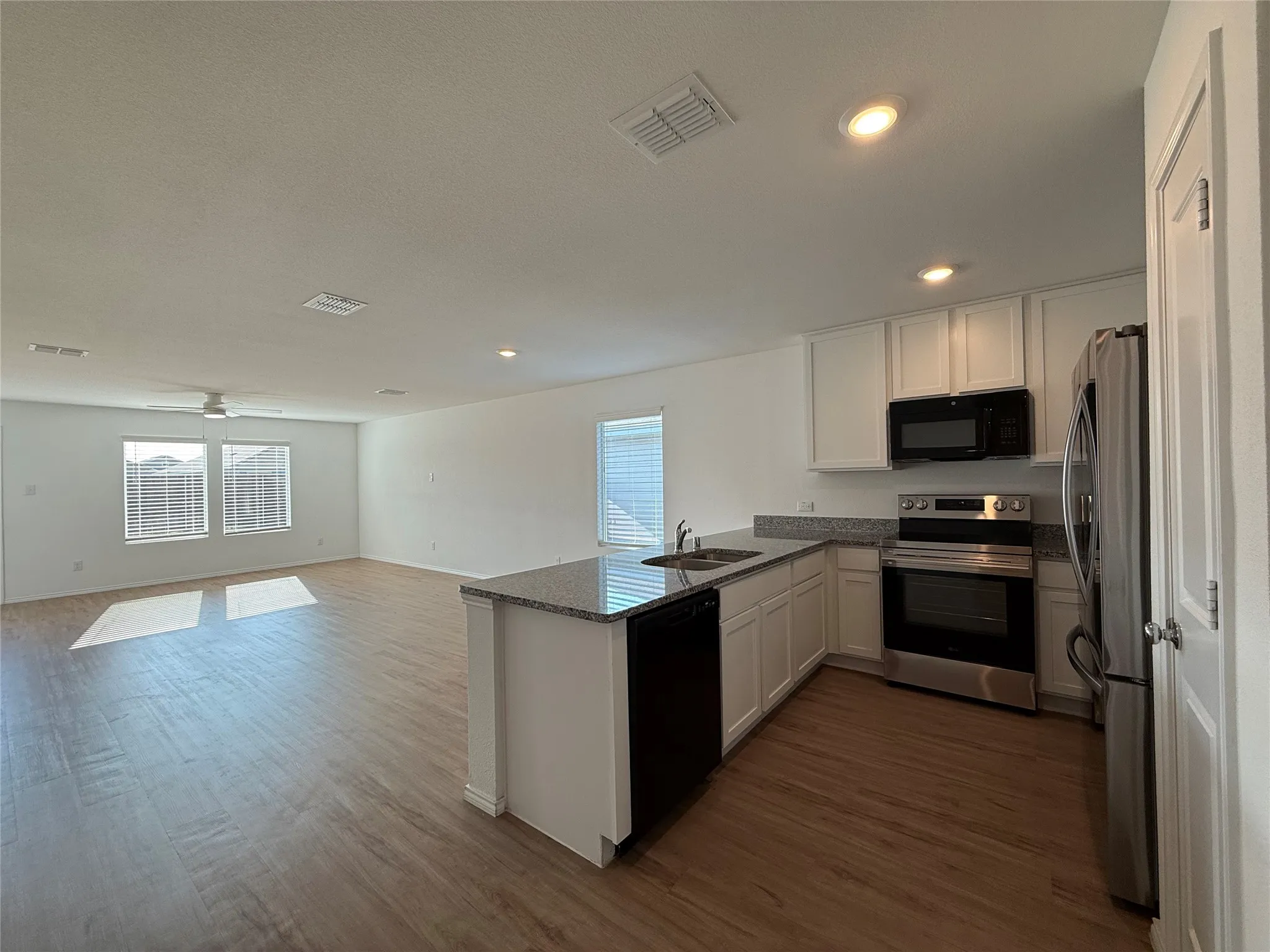 Open-concept layout featuring wood-finish flooring, recessed lighting, and a ceiling fan