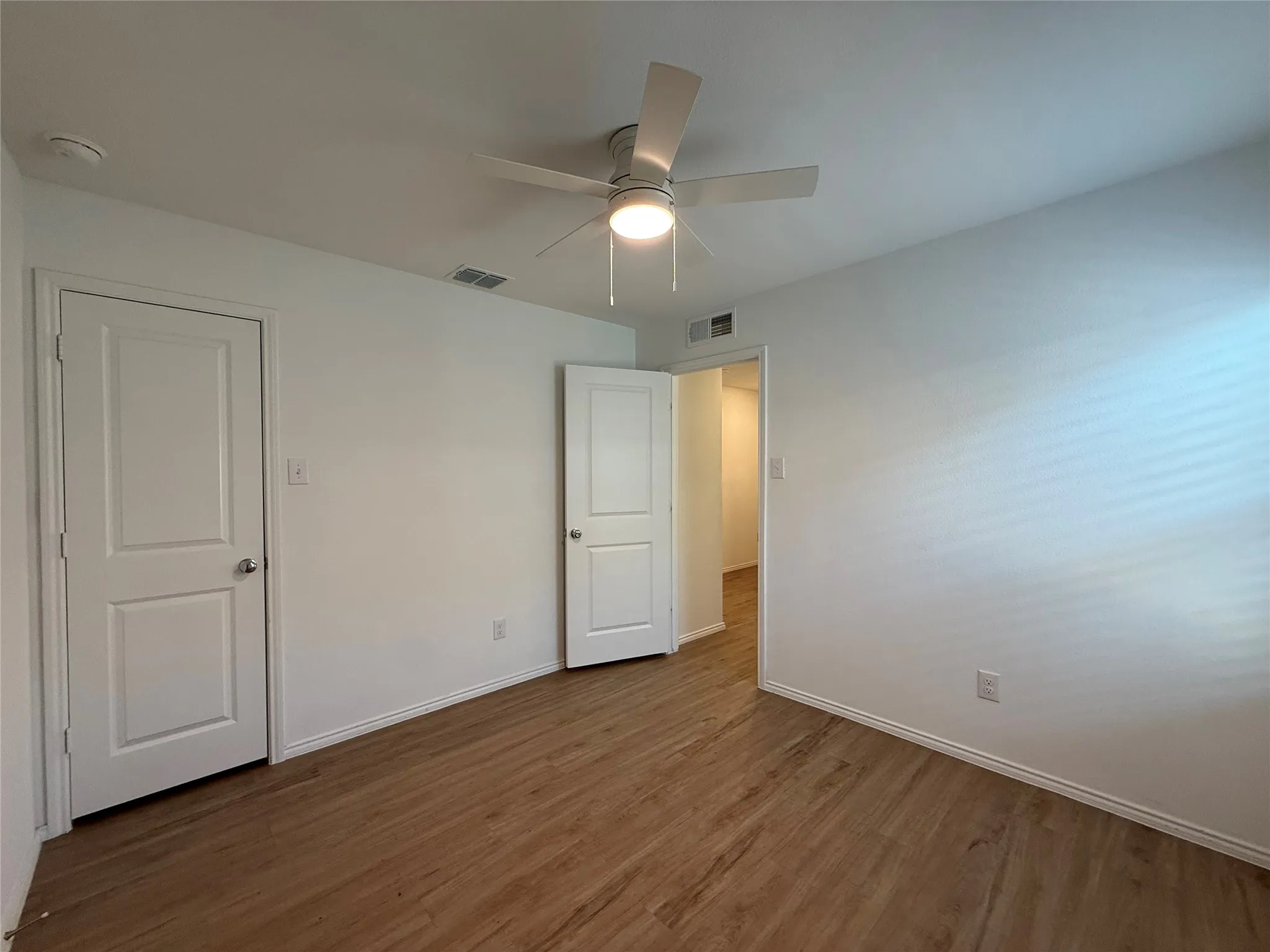Wood-finish flooring, white walls, white trim, recessed lighting, and a white ceiling fan with integrated lighting