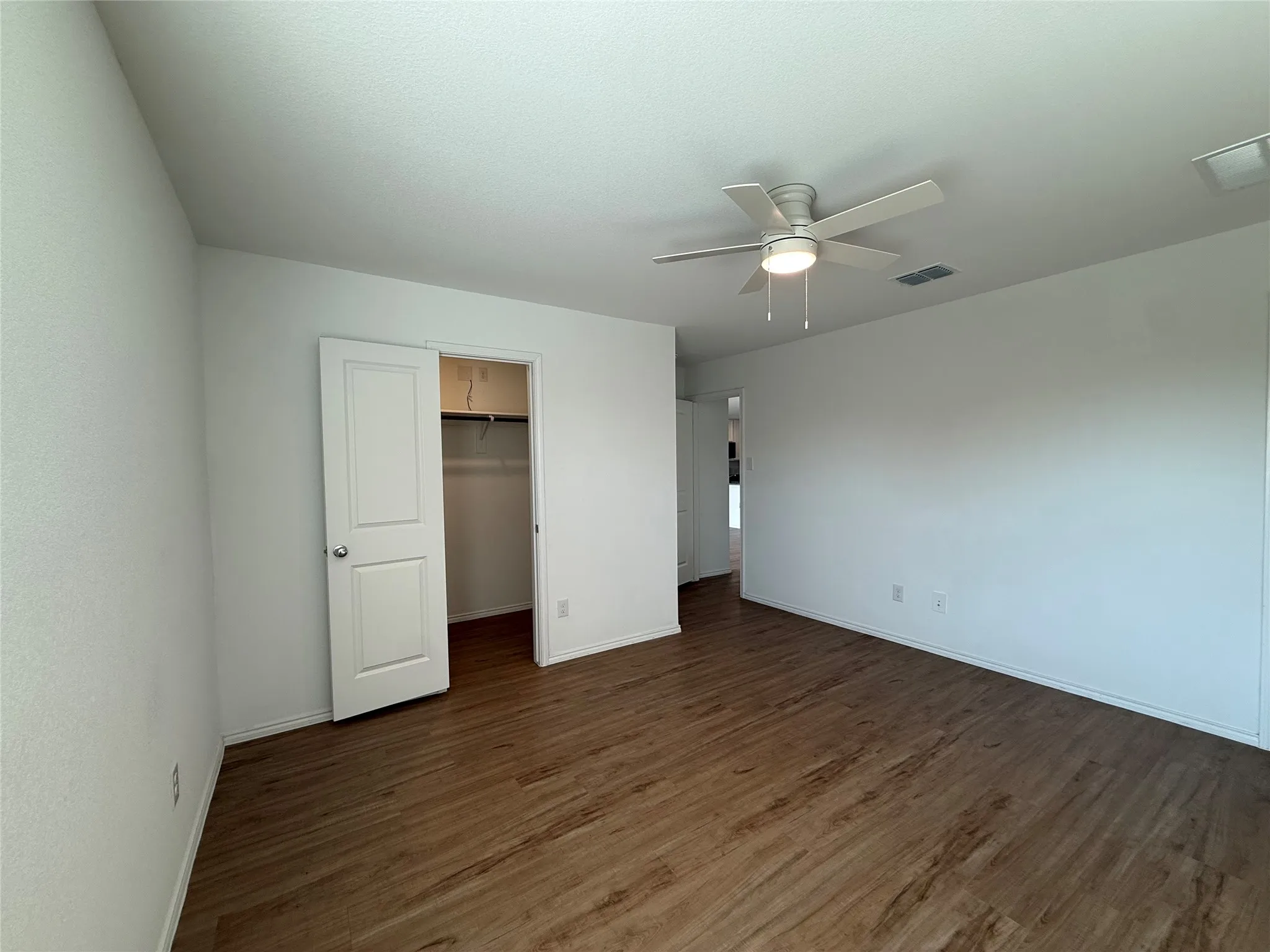 Wood-finish flooring, white walls, ceiling fan with integrated lighting, and a bi-fold closet door