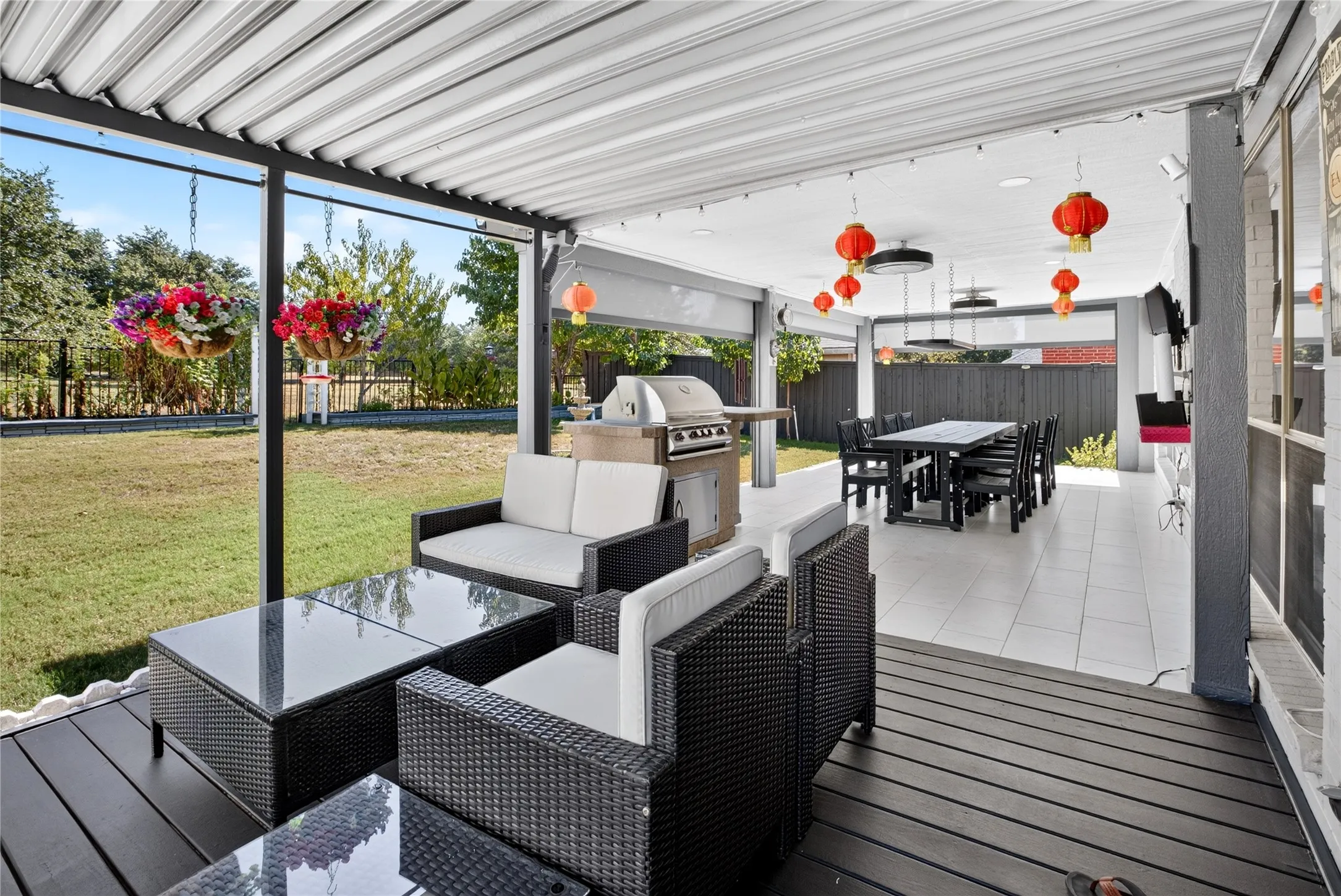 Expansive covered patio featuring a dark wood-finish deck, tiled outdoor area, and a outdoor grill