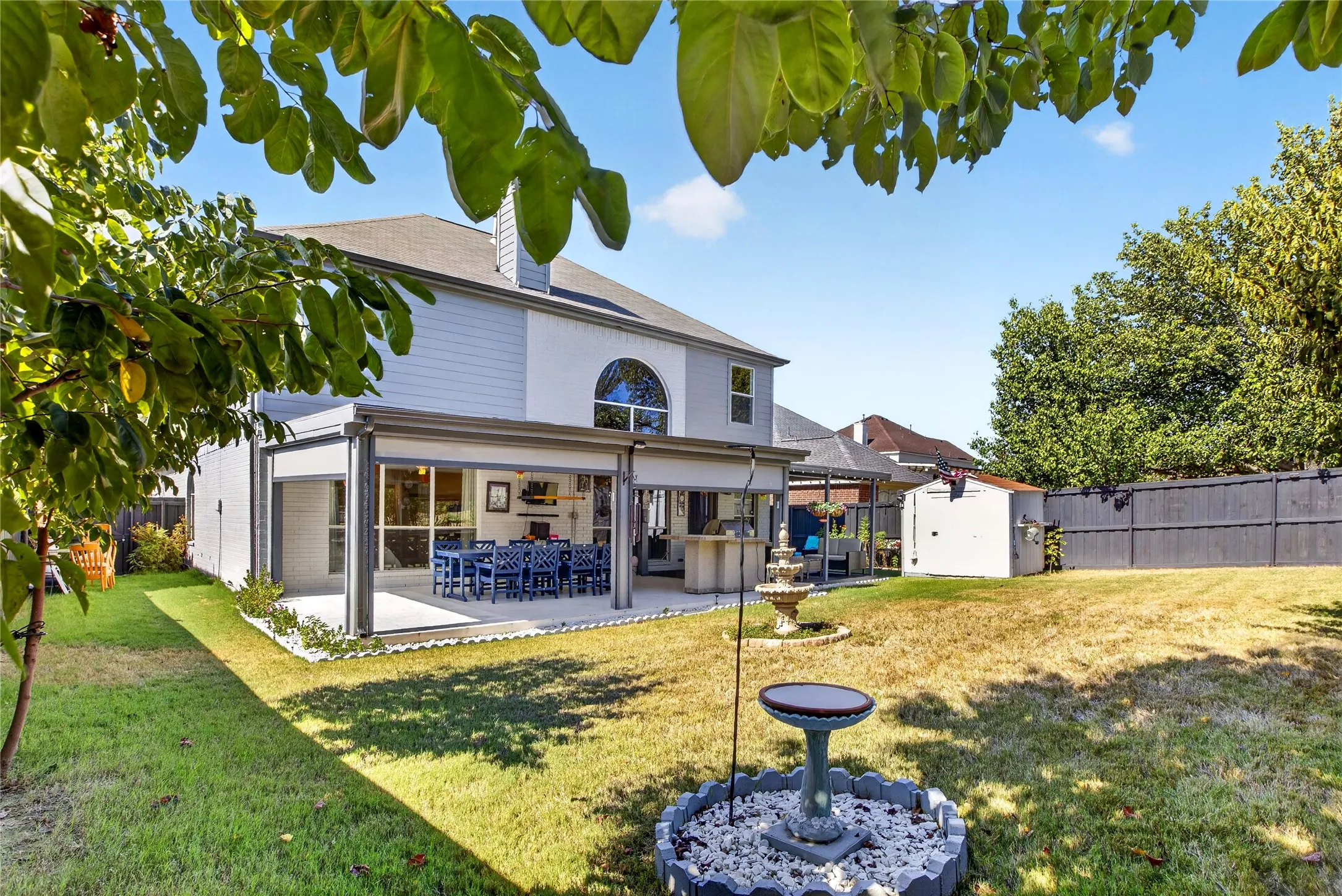 Spacious backyard featuring an expansive covered patio, large arched window, and a built-in outdoor bar