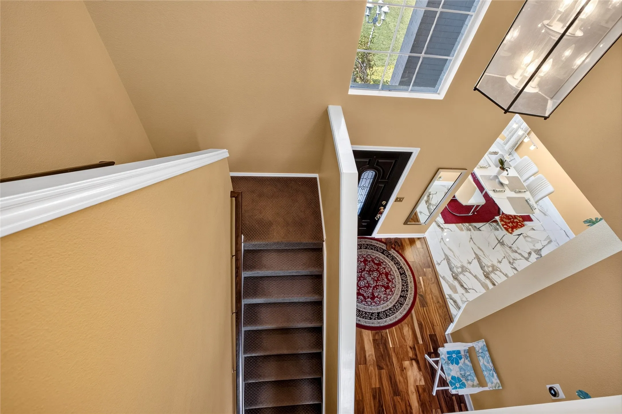 Two-story foyer with a skylight, wood-finish flooring, and a decorative front door