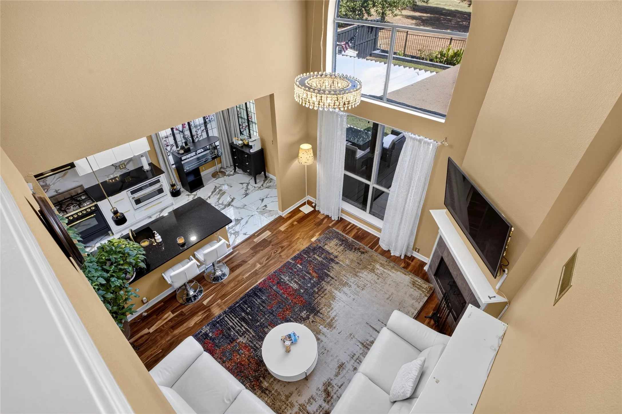 Two-story living area with high ceilings, a contemporary chandelier, and large windows